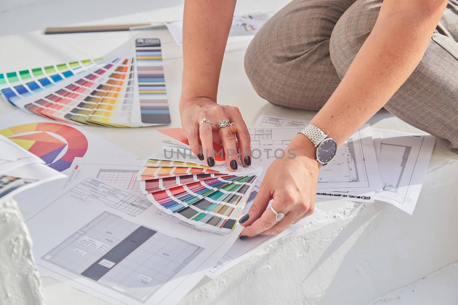 Close-up view of interior designer woman's hands working with color palette and interior plans for a new project with soft focus..