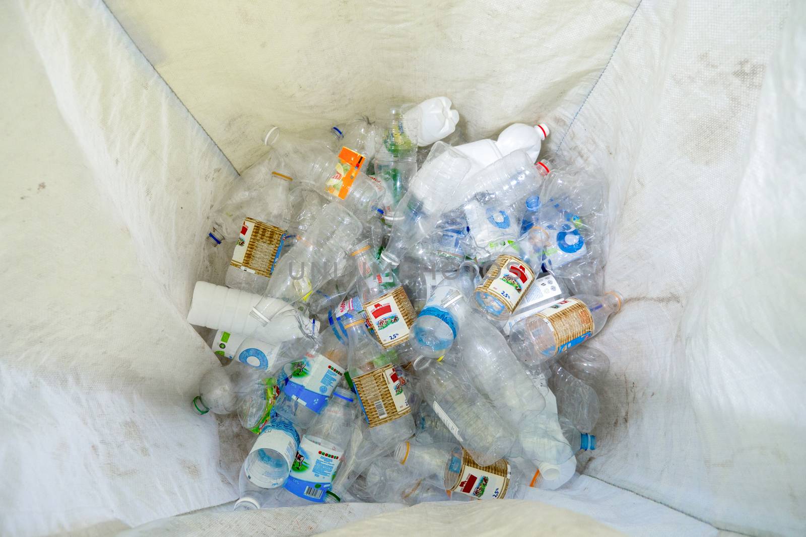 Plastic bottles. Recycle waste management concept. Plastic bottle in recyclable waste. White urn with plastic at the bottom. View from the top. White clean urn for plastic. Activists against waste