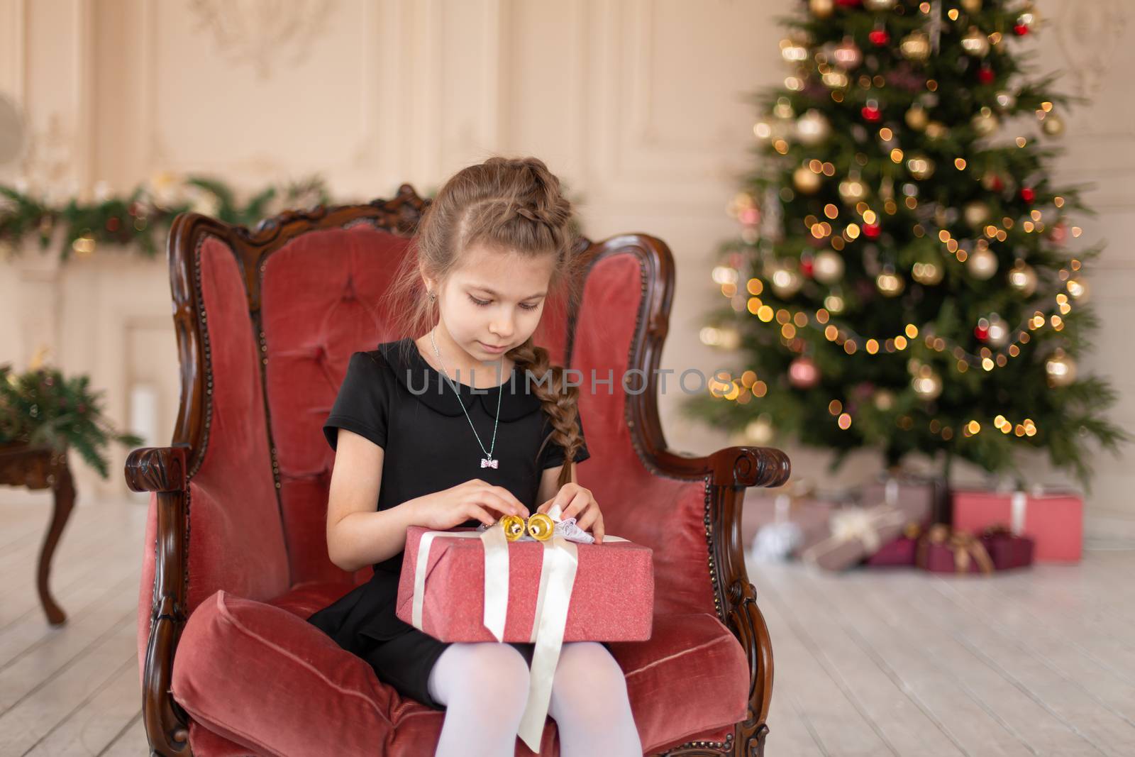 A little girl opens a Christmas present from Santa. Christmas tale. Happy childhood.