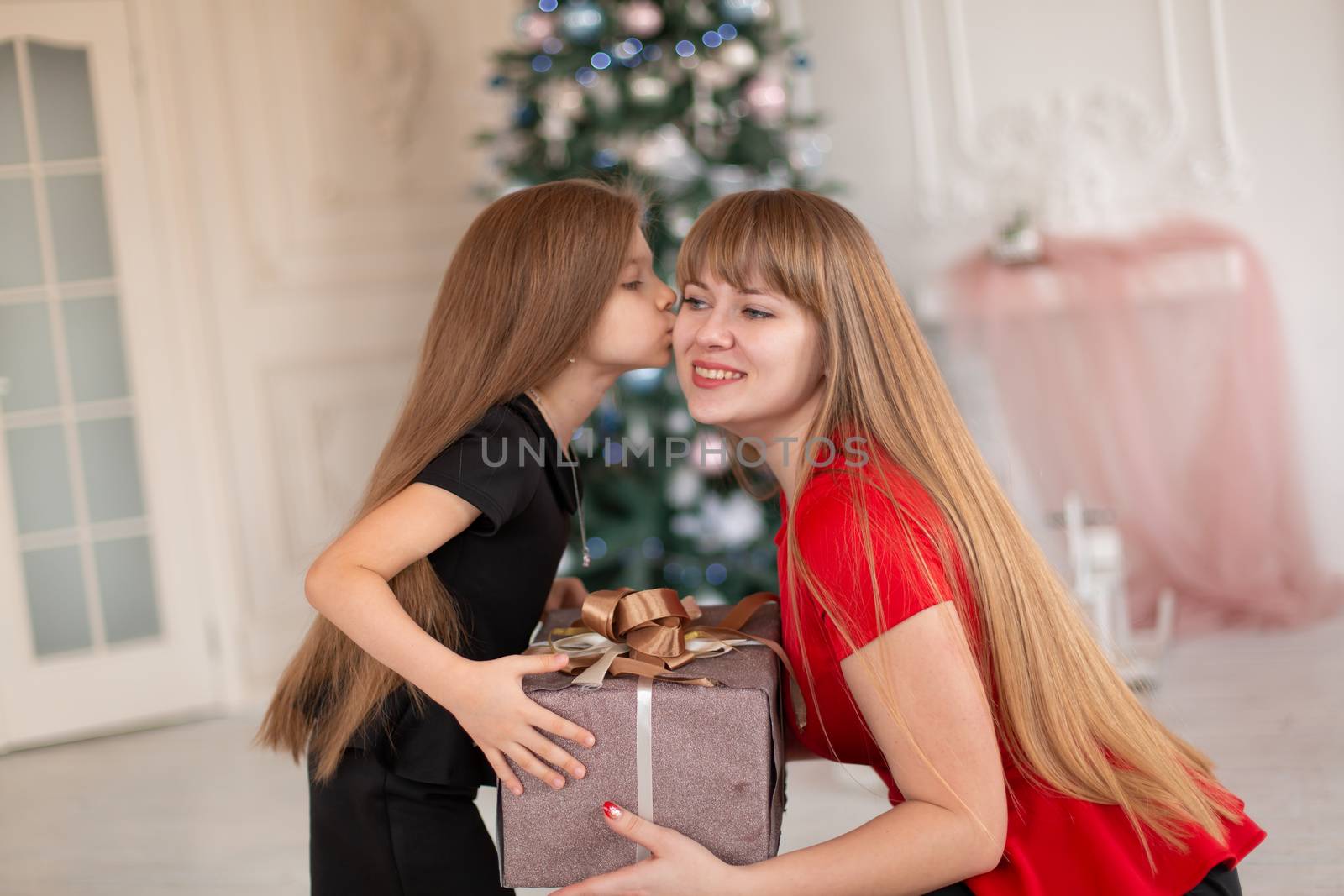 Little girl gives her mom a box with a Christmas present.