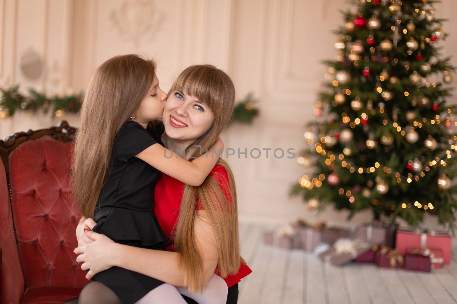 Little girl hugs her mom near the Christmas tree. Joyful moments of a happy childhood by Try_my_best