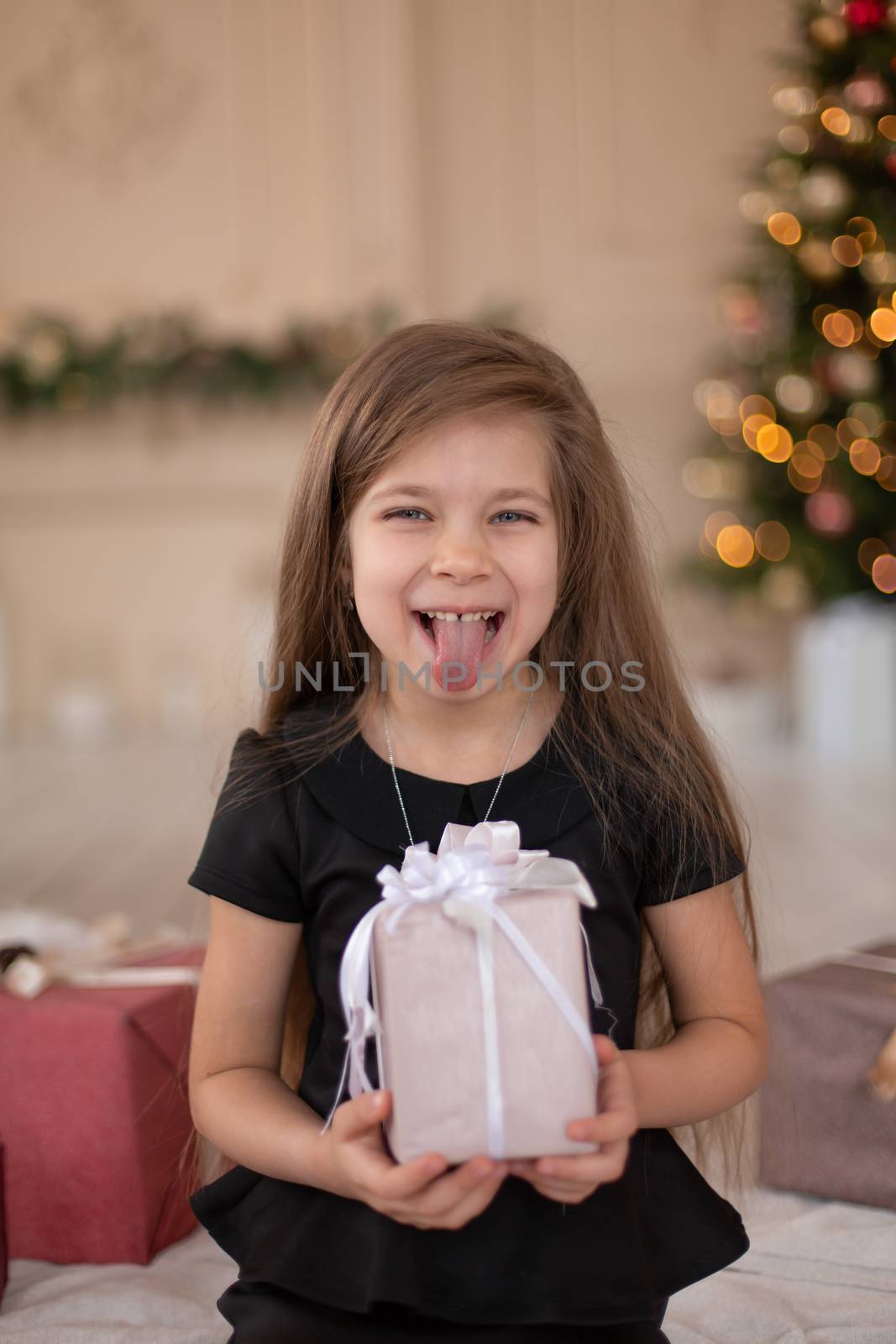 A little girl opens a Christmas present from Santa. Christmas tale. Happy childhood.