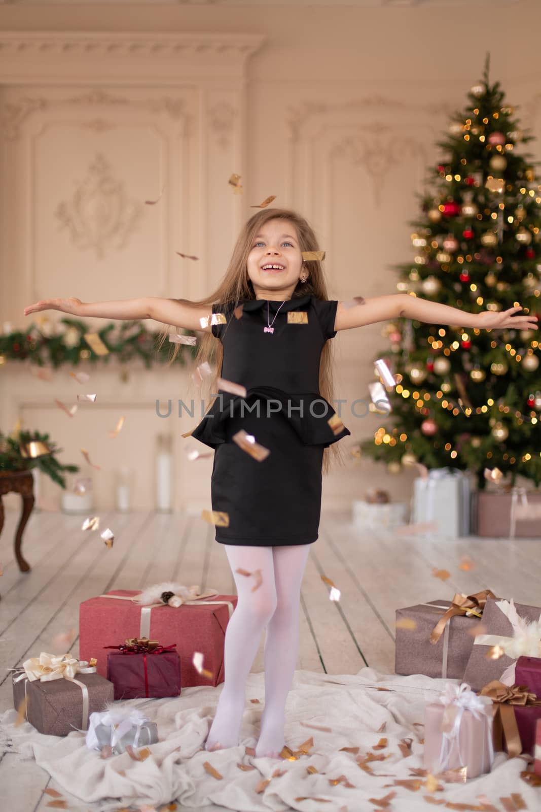 Little girl throws confetti. Christmas magic. Joyful moments of a happy childhood.