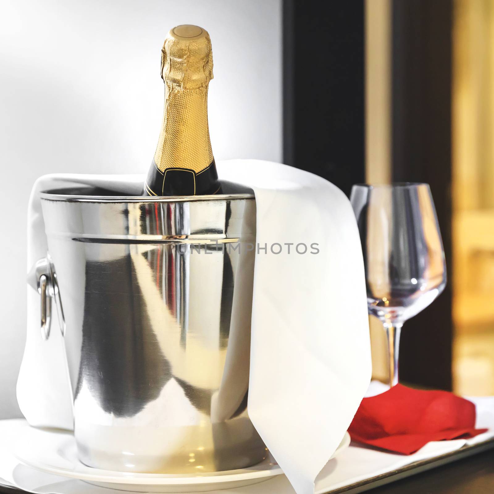 Champagne in ice bucket. Bottle of cold wine or champagne in ice bucket on white table at hotel room. Wedding reception, holiday concept.