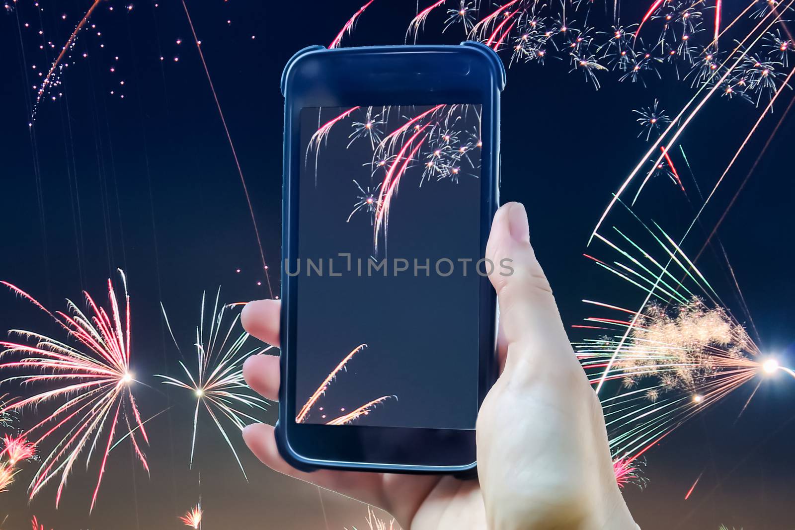 Fireworks composing of a female hand holding a smartphone taking a picture