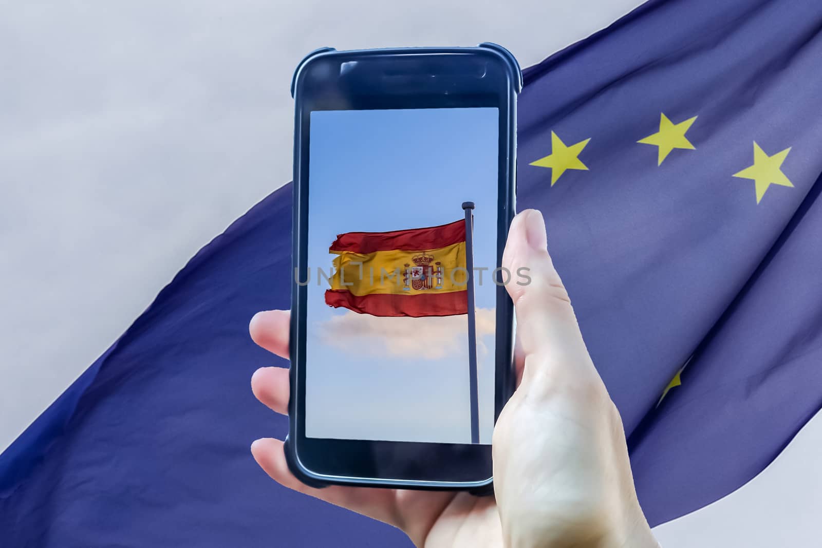 Spain flag in a smartphone display in front of a european union flag