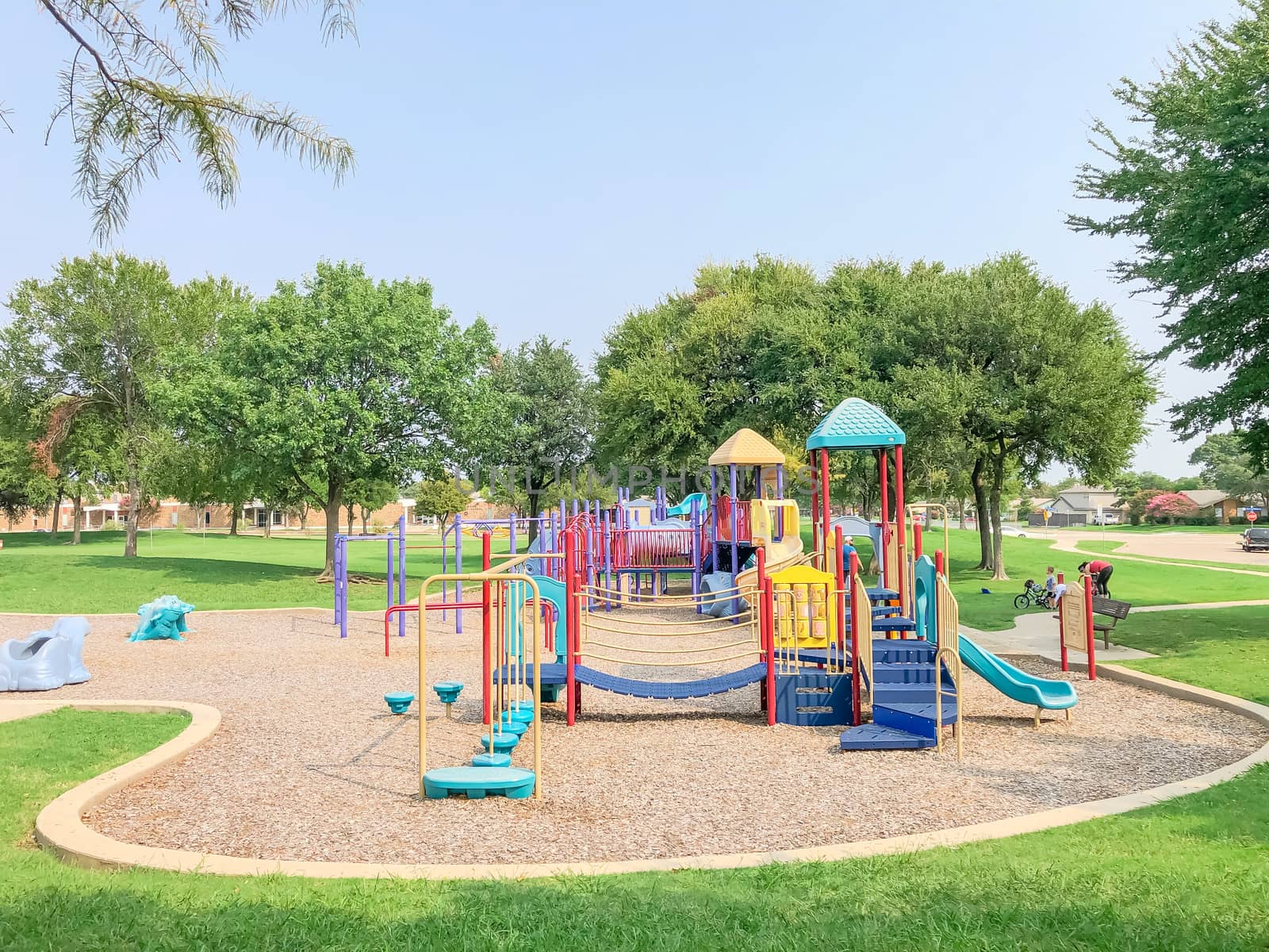 Colorful playground near residential neighborhood in Richardson, Texas, America. Community facility surrounded by large oak trees and green grass lawn