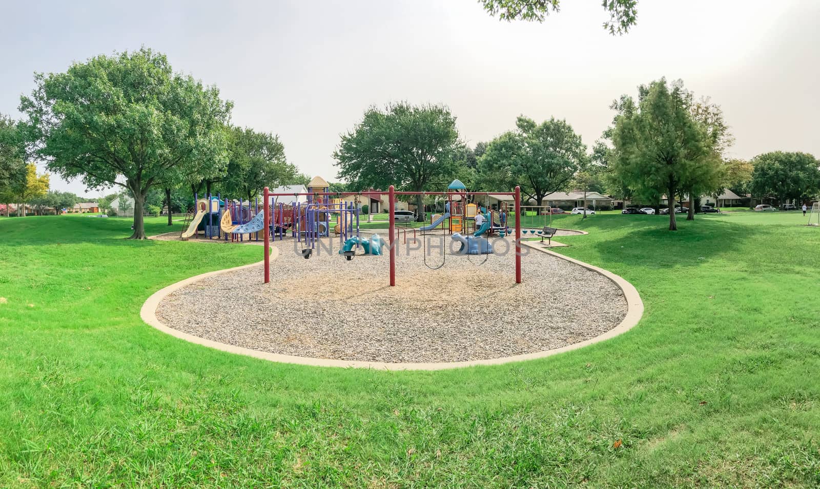Swing set at large playground in residential neighborhood near Dallas, Texas, America. Community park with row of single family houses in background