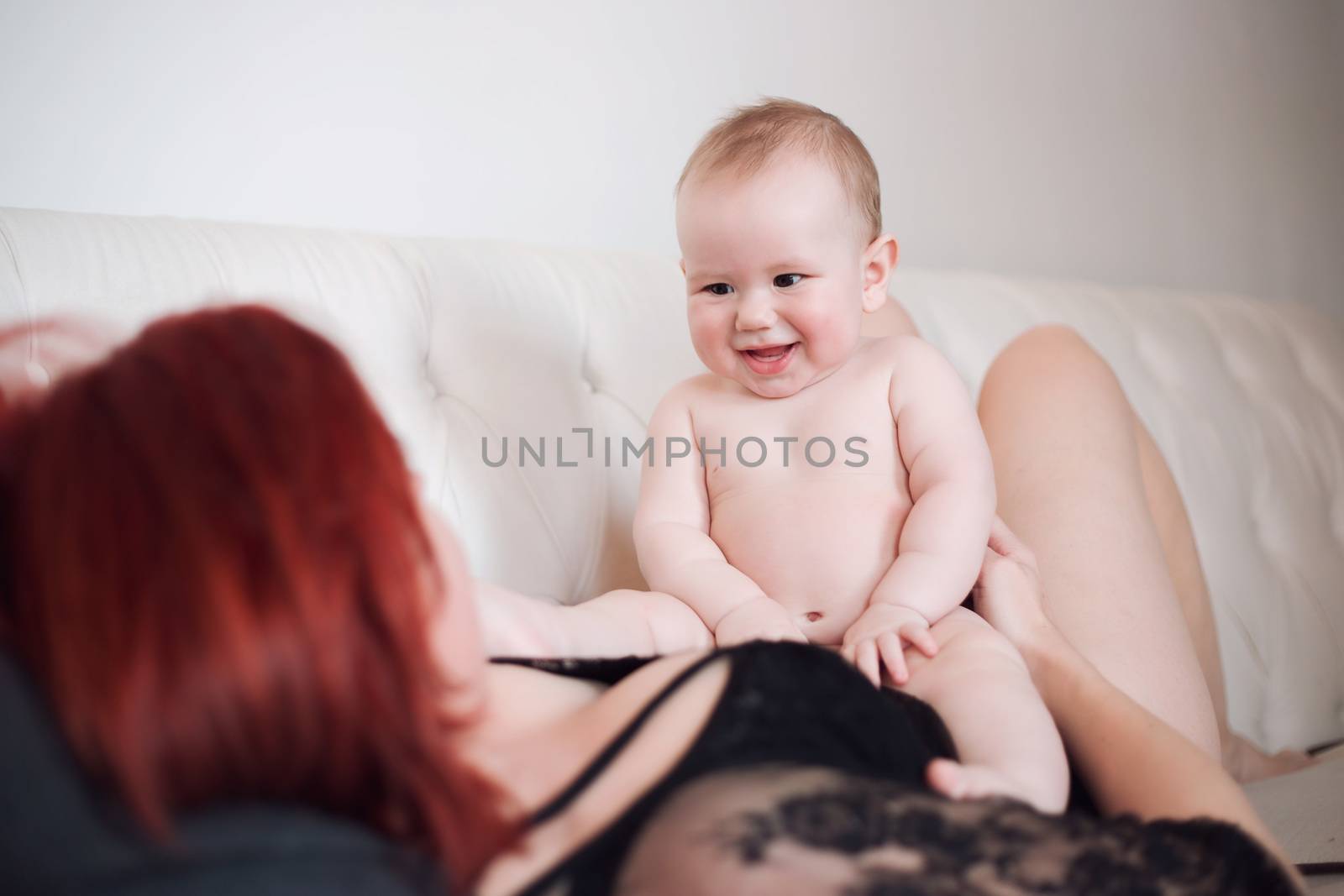 The baby boy sits astride mom's belly and smiles