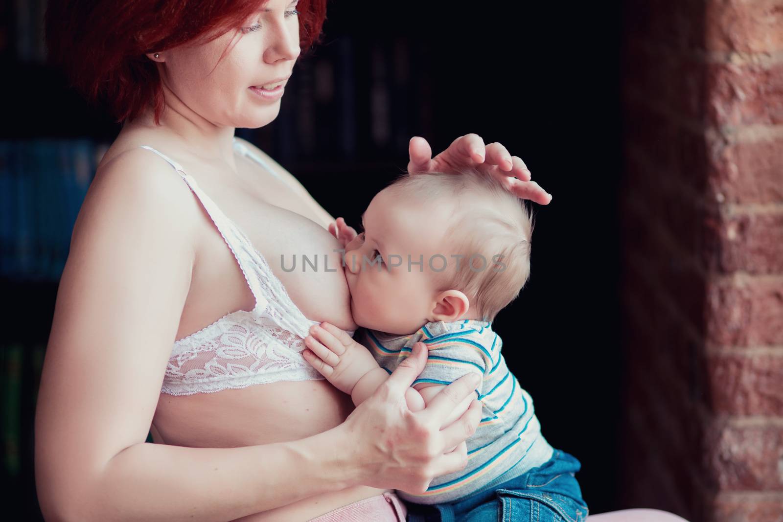 A young mother is breastfeeding her little child and looking at him tenderly