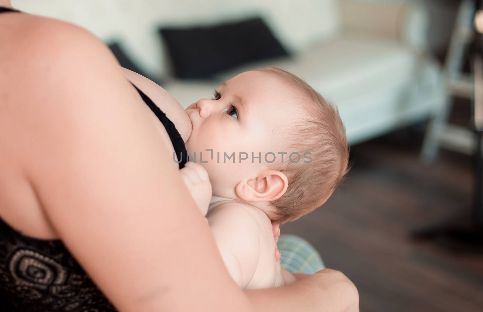 A young mother is breastfeeding her little child and looking at him tenderly