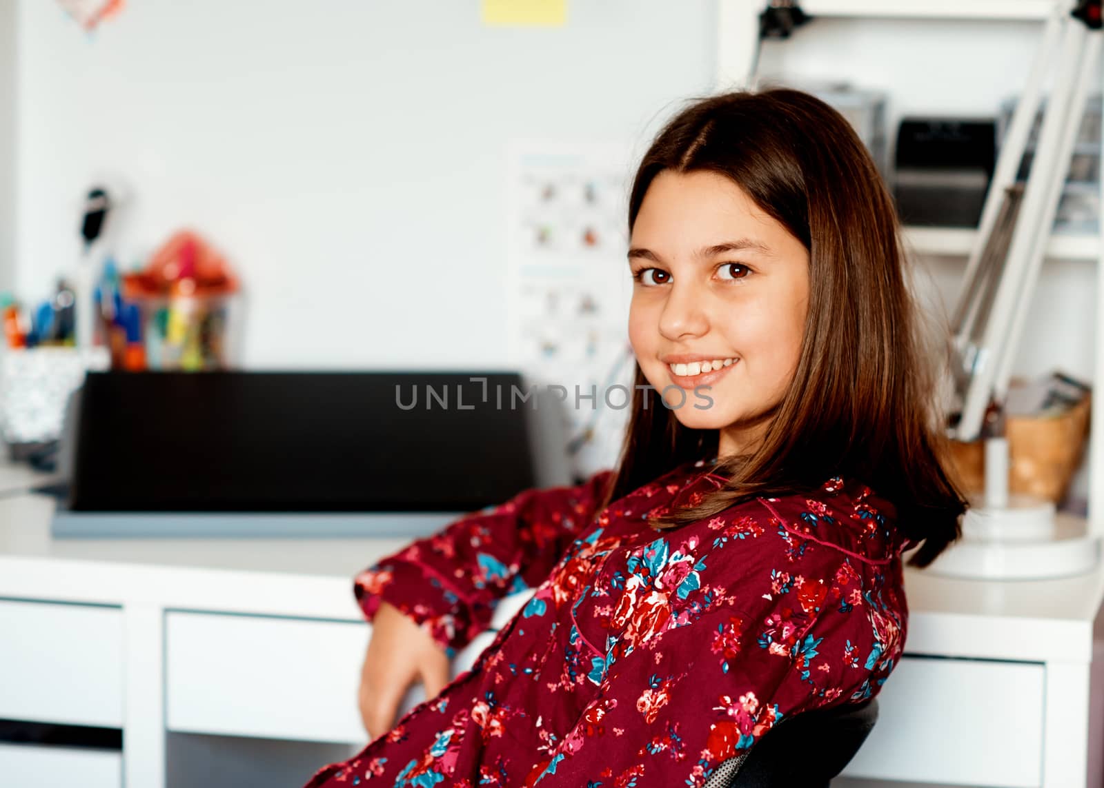 Portrait of a girl in pajamas sitting at the table and smiling