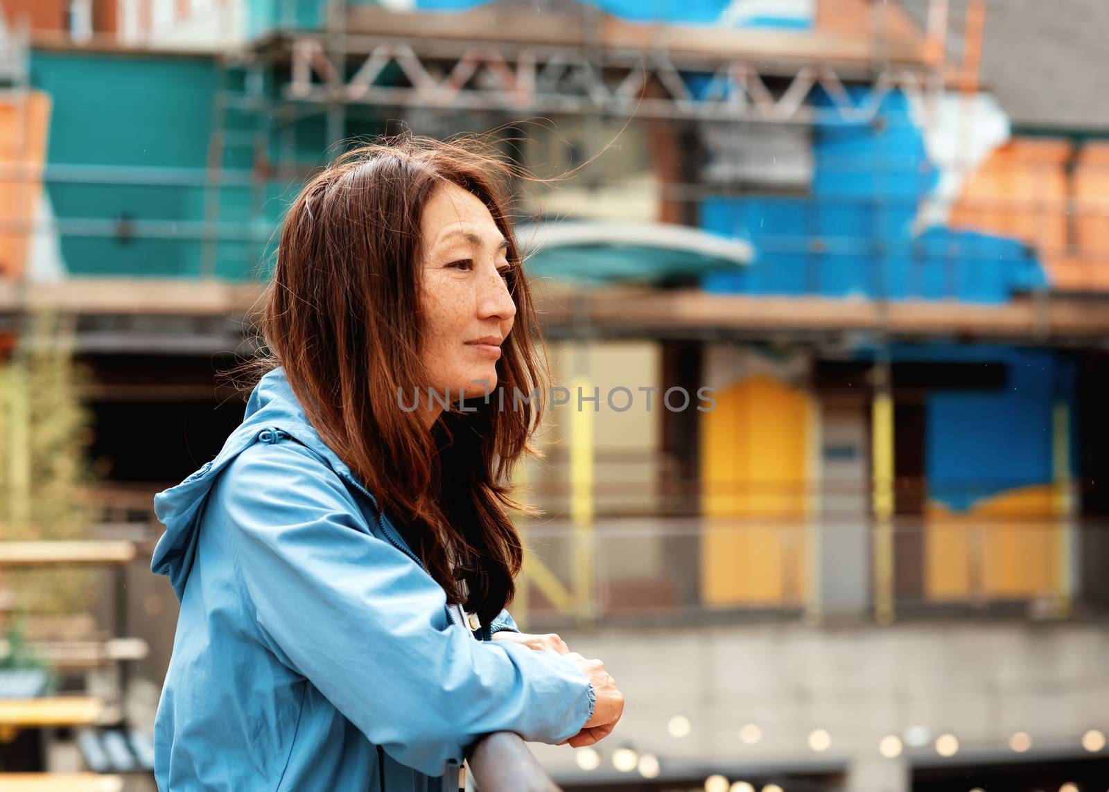 Asian woman in a blue coat walking around Europe city by Iryna_Melnyk
