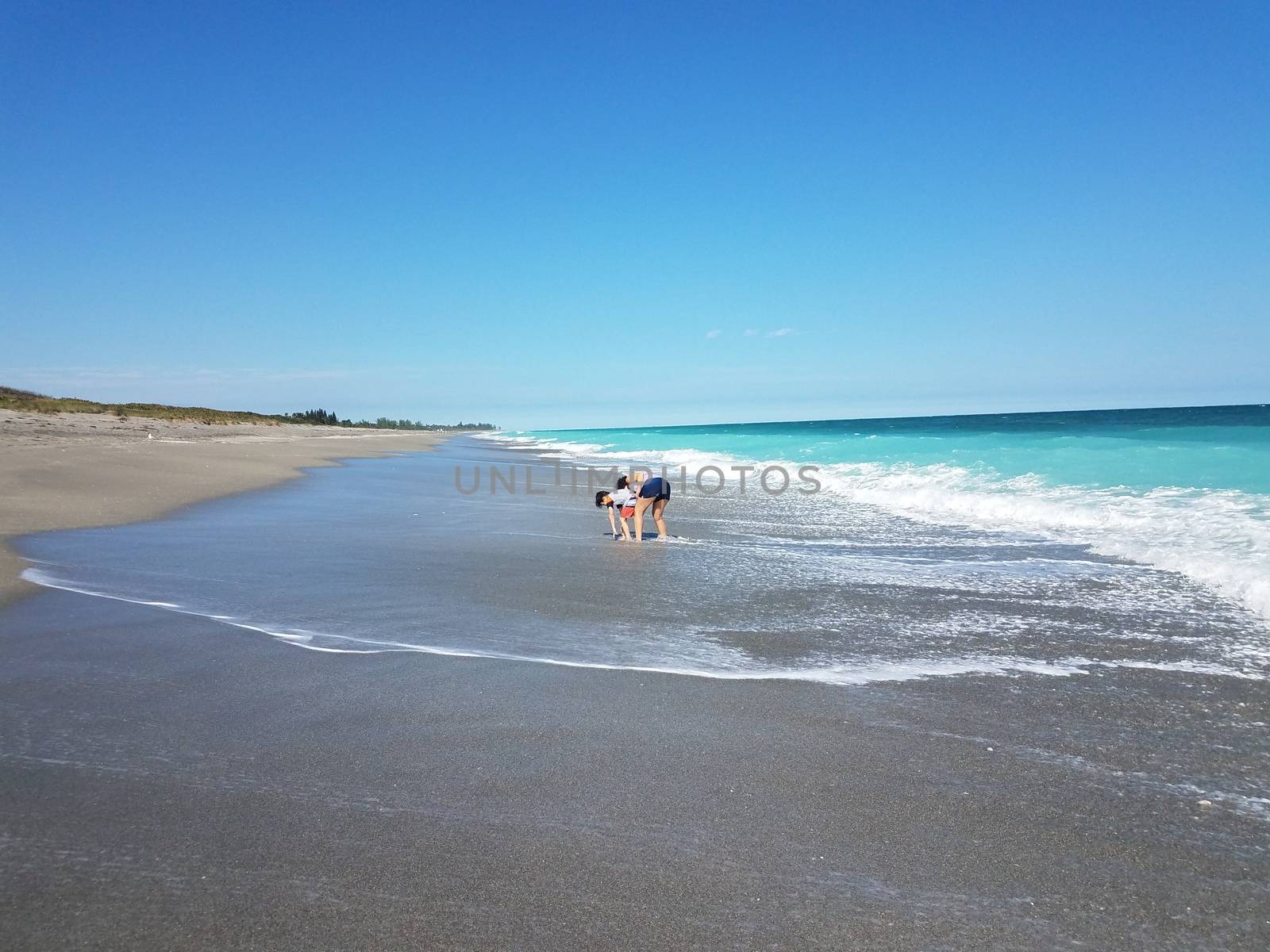 mother and child playing on the beach with waves by stockphotofan1