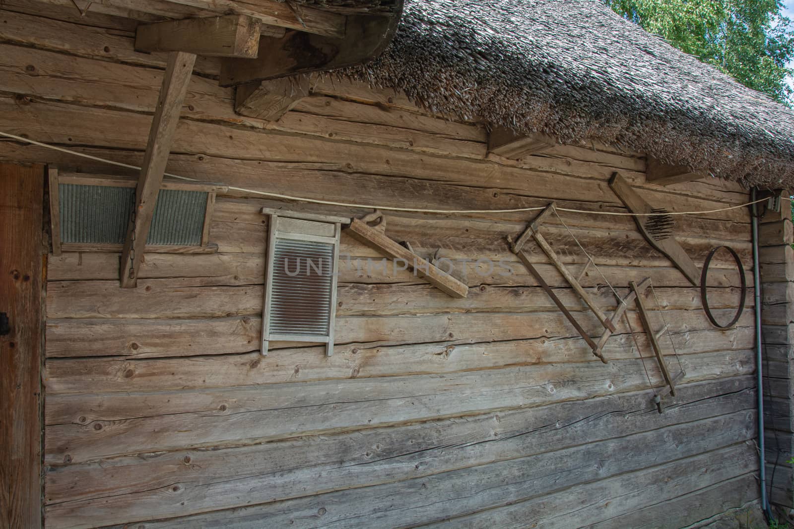 wall of a log village hut with hand tools for farming and everyday life