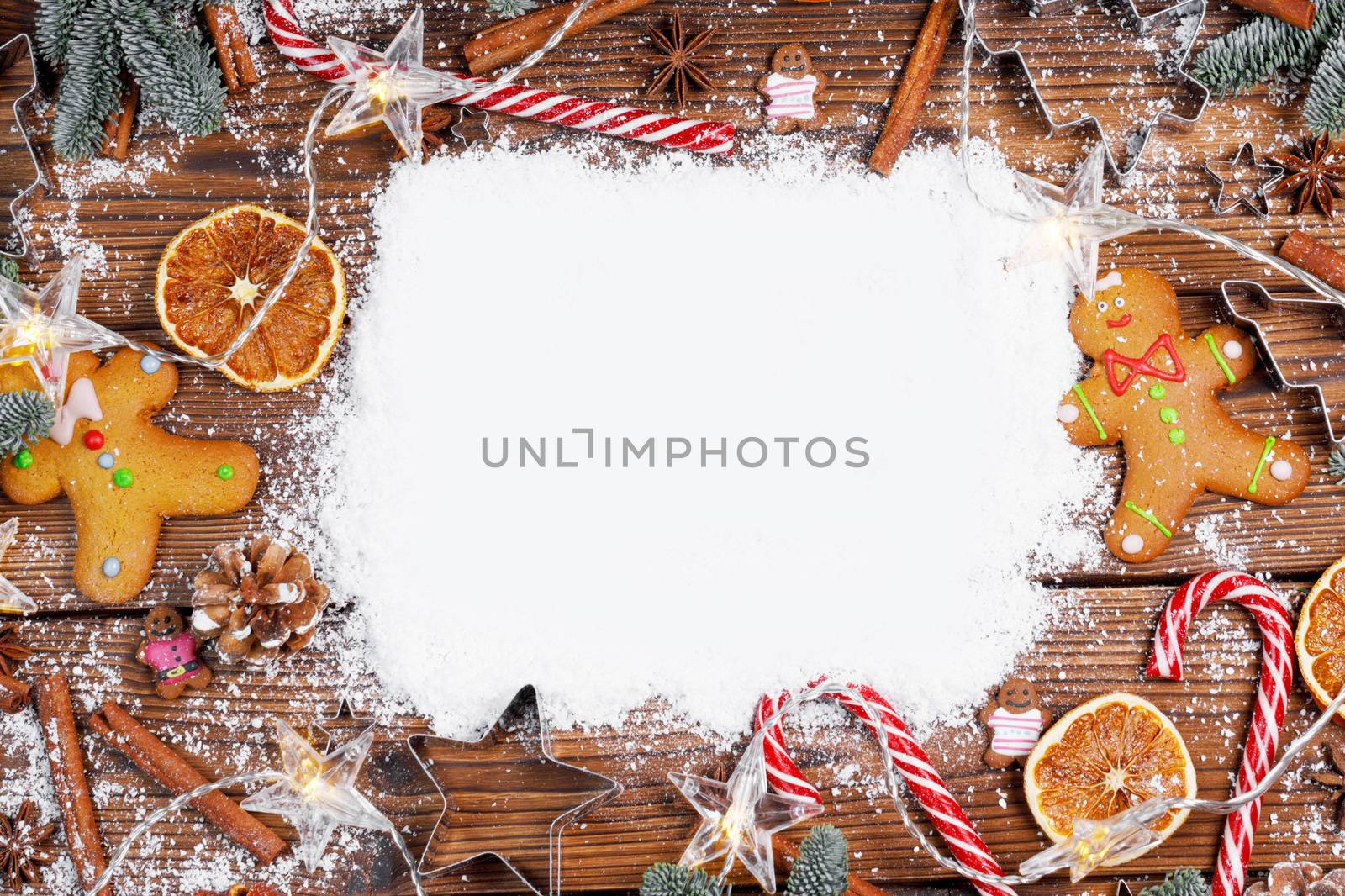 Christmas food frame. Gingerbread cookies, spices and decorations on wooden background with white copy space on snow