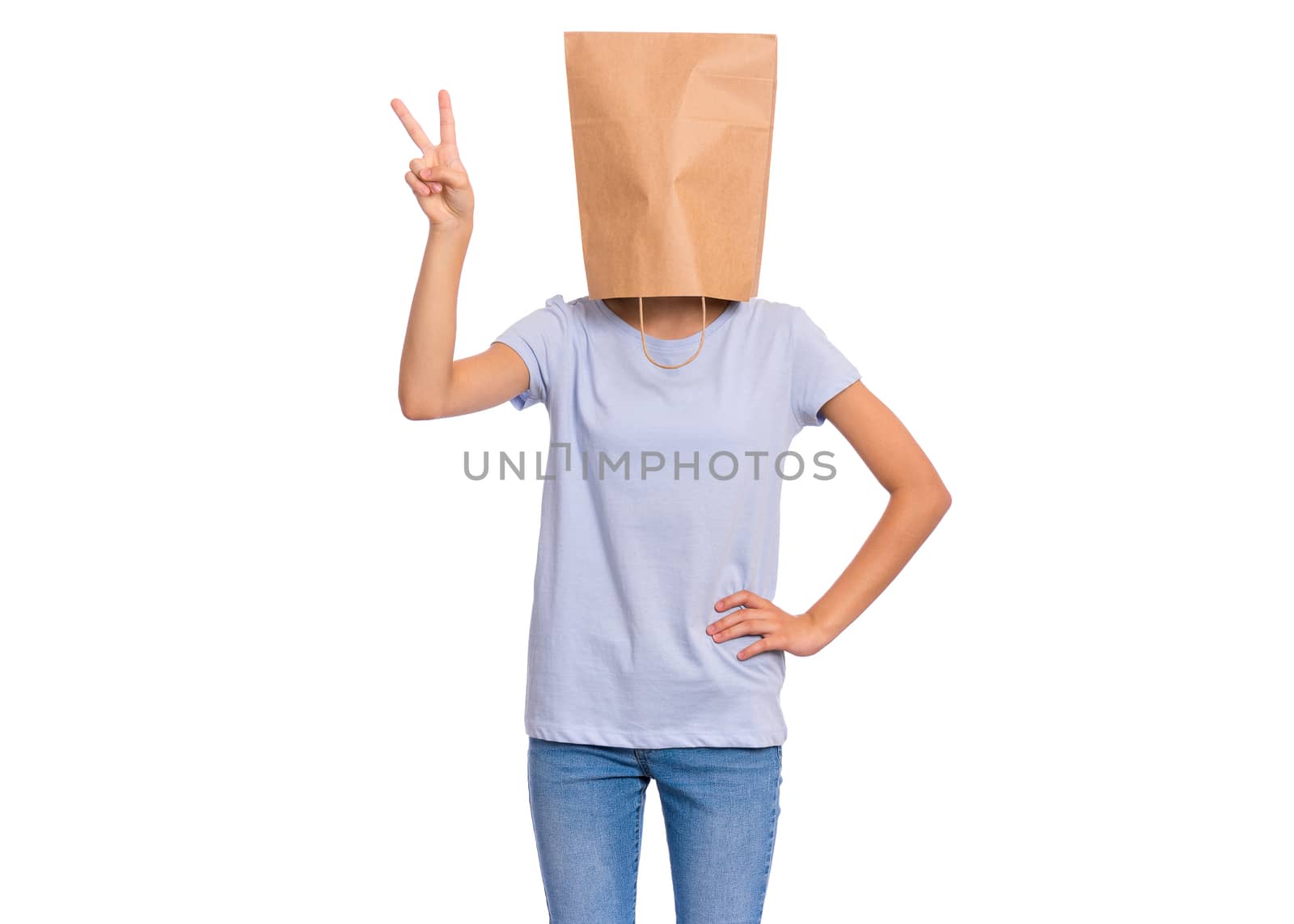 Portrait of teen girl with paper bag over head making Victory gesture. Teenager showing victory sign isolated on white background. Happy child posing in studio.