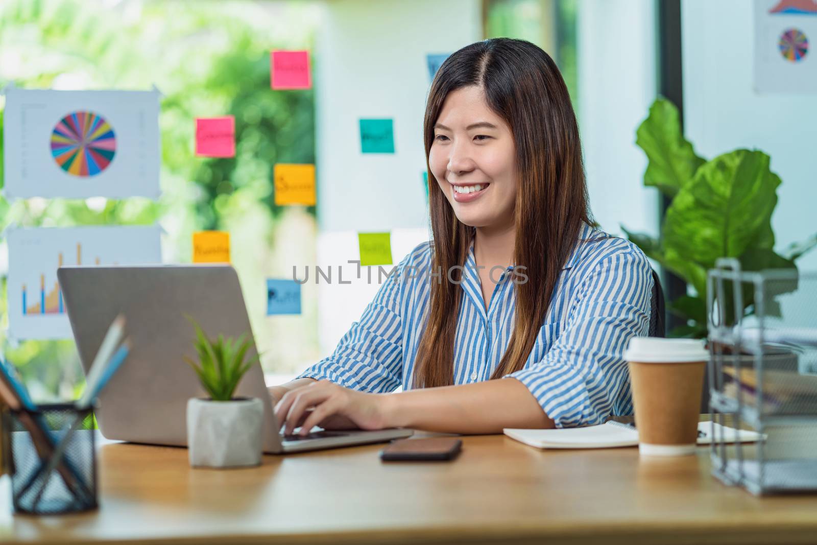 Asian Businesswoman sitting and working with technology laptop i by Tzido