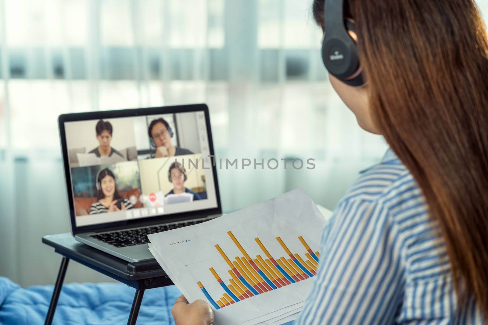 Rear view of Asian woman working and online meeting via video co by Tzido