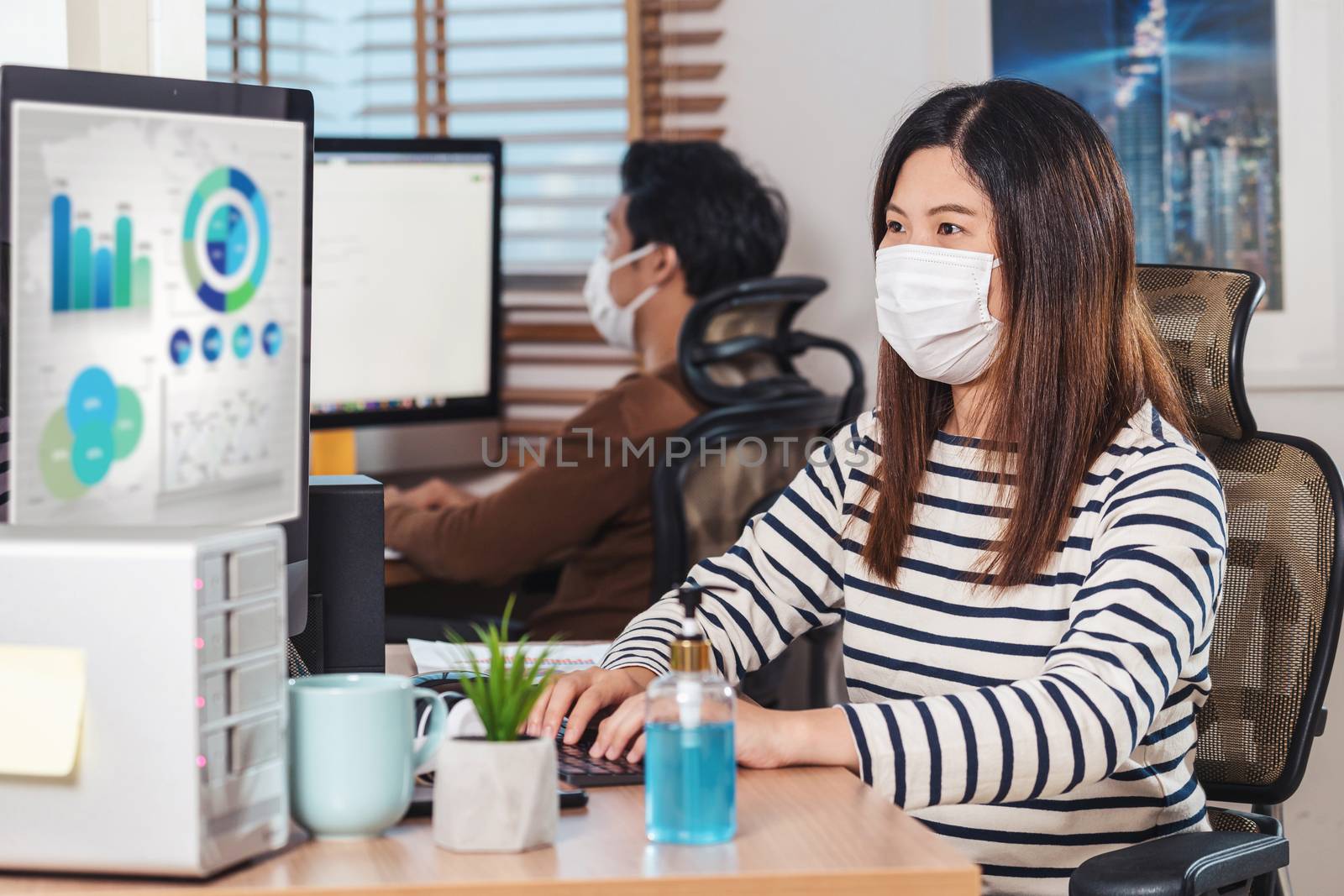Couple of Asian colleagues wearing the surgical mask and working by Tzido
