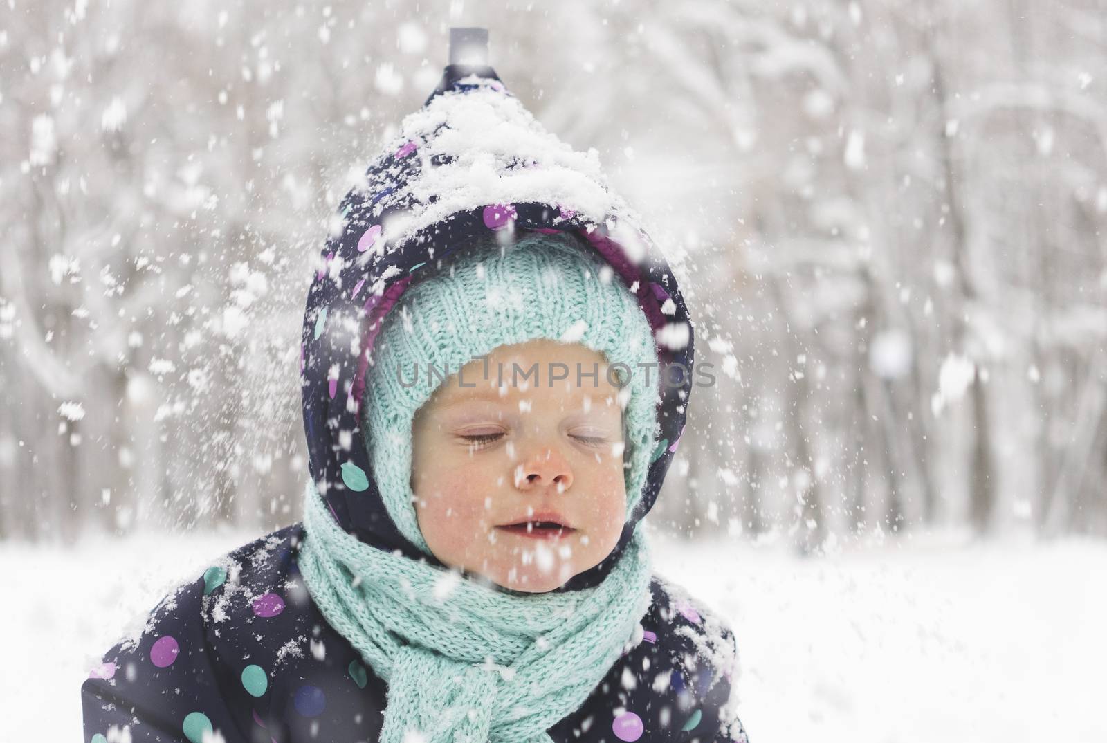 Baby in a winter jumpsuit rejoices in the first snow