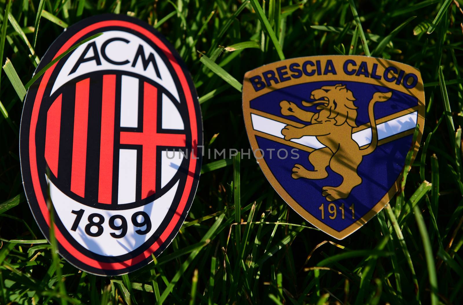September 6, 2019, Turin, Italy. Emblems of Italian football clubs Brescia and Milan on the green grass of the lawn.
