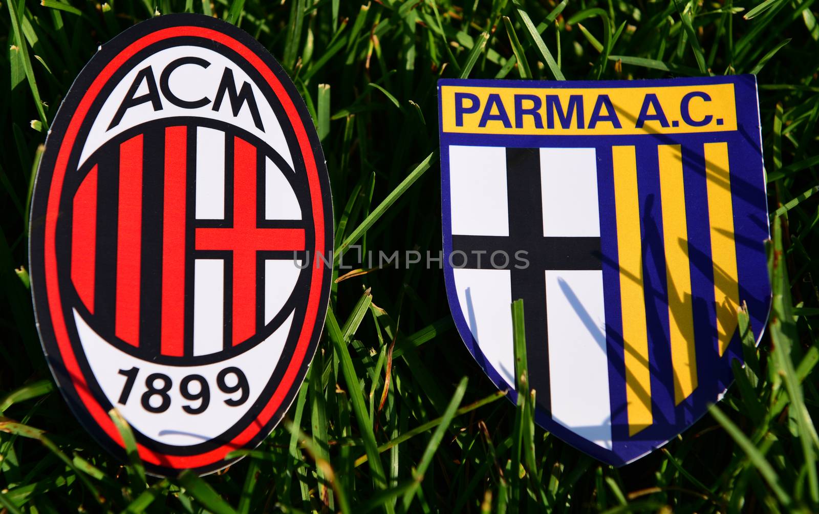 September 6, 2019, Turin, Italy. Emblems of Italian football clubs Milan and Parma on the green grass of the lawn.