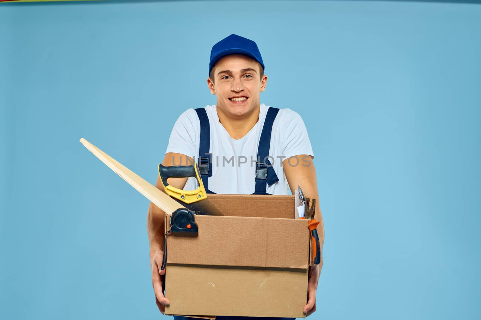working man in uniform box with tools loader delivery blue background. High quality photo