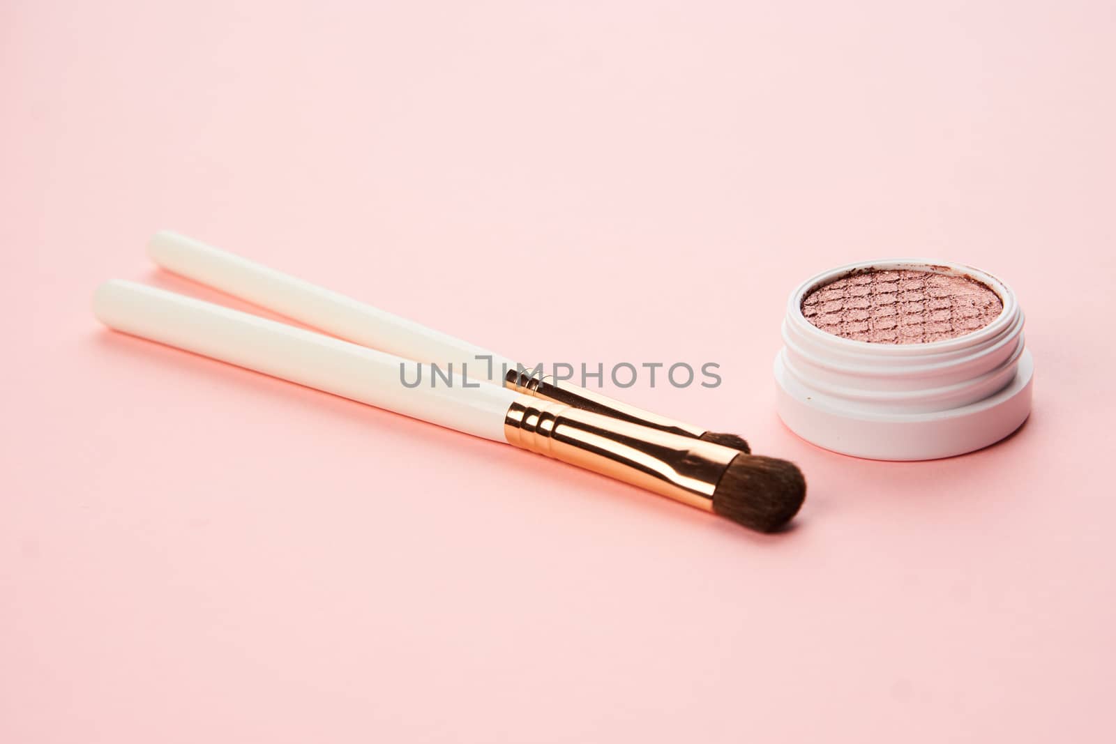 makeup brushes and eyeshadow professional cosmetics on pink background by SHOTPRIME