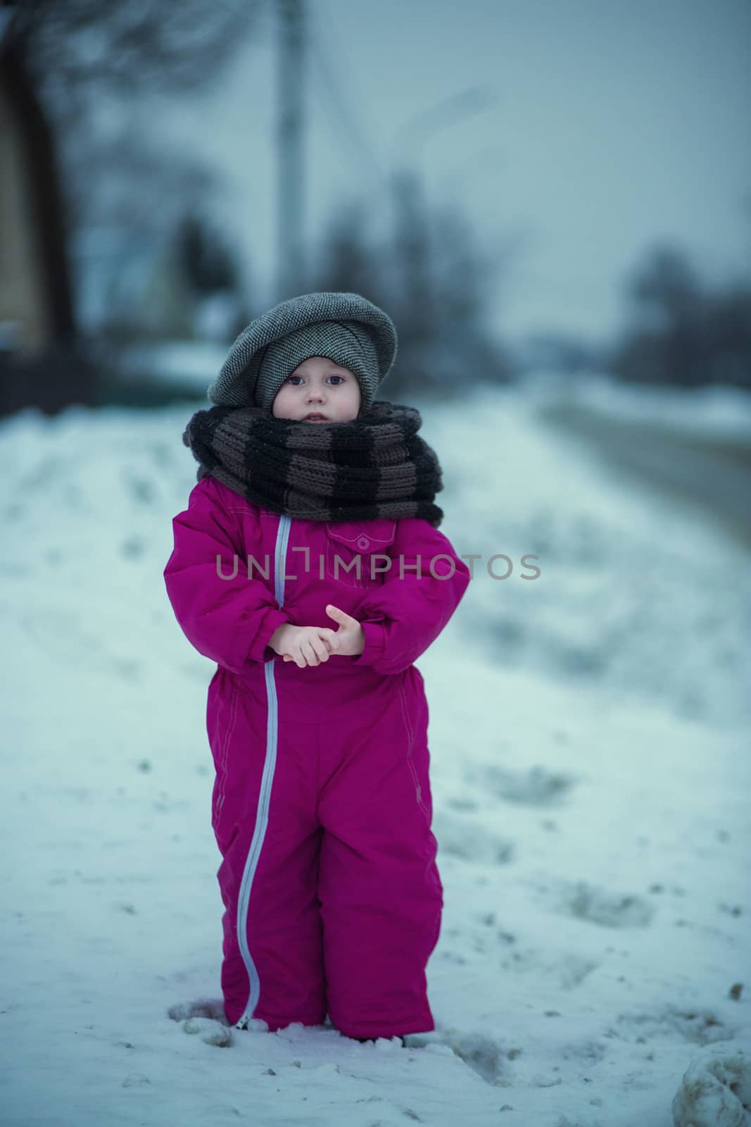 .A little girl stands in the snow by the road in the evening  by galinasharapova