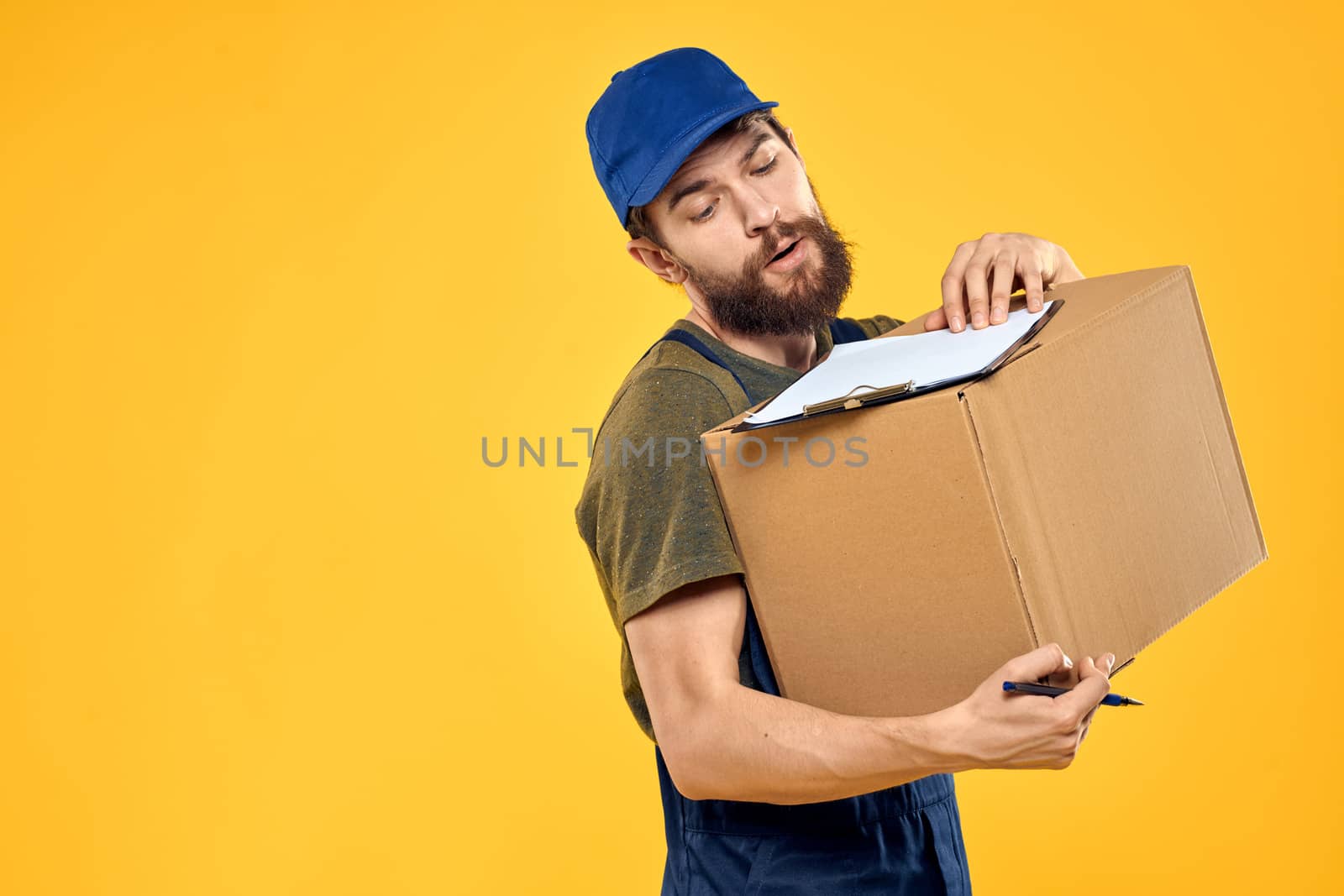 Worker male courier delivering boxes packaging documents yellow background by SHOTPRIME