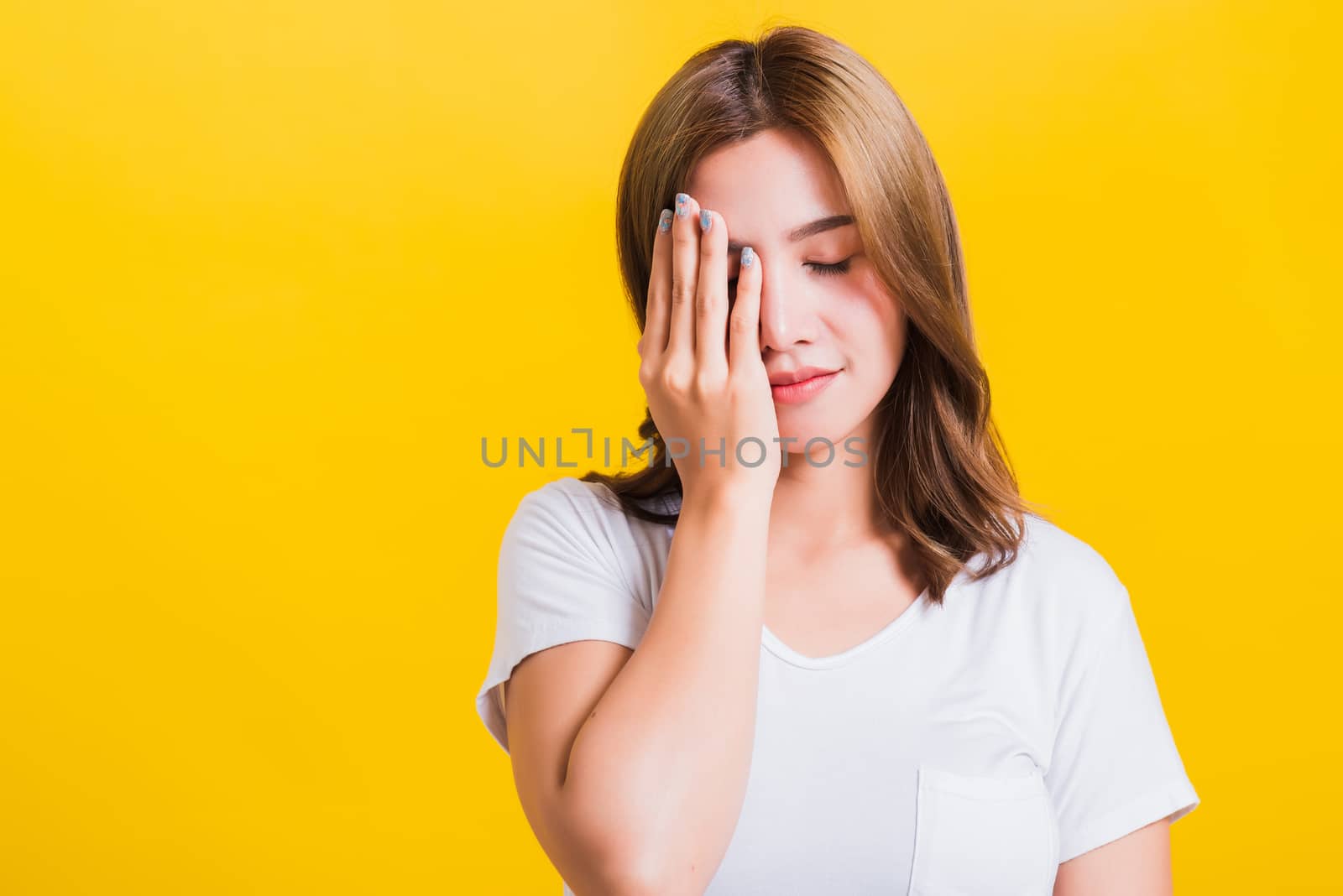 Portrait Asian Thai beautiful young woman emotions tired and sleepy her yawning close mouth open by hand, shoot a photo in the studio on yellow background, There was copy space, insomnia concept