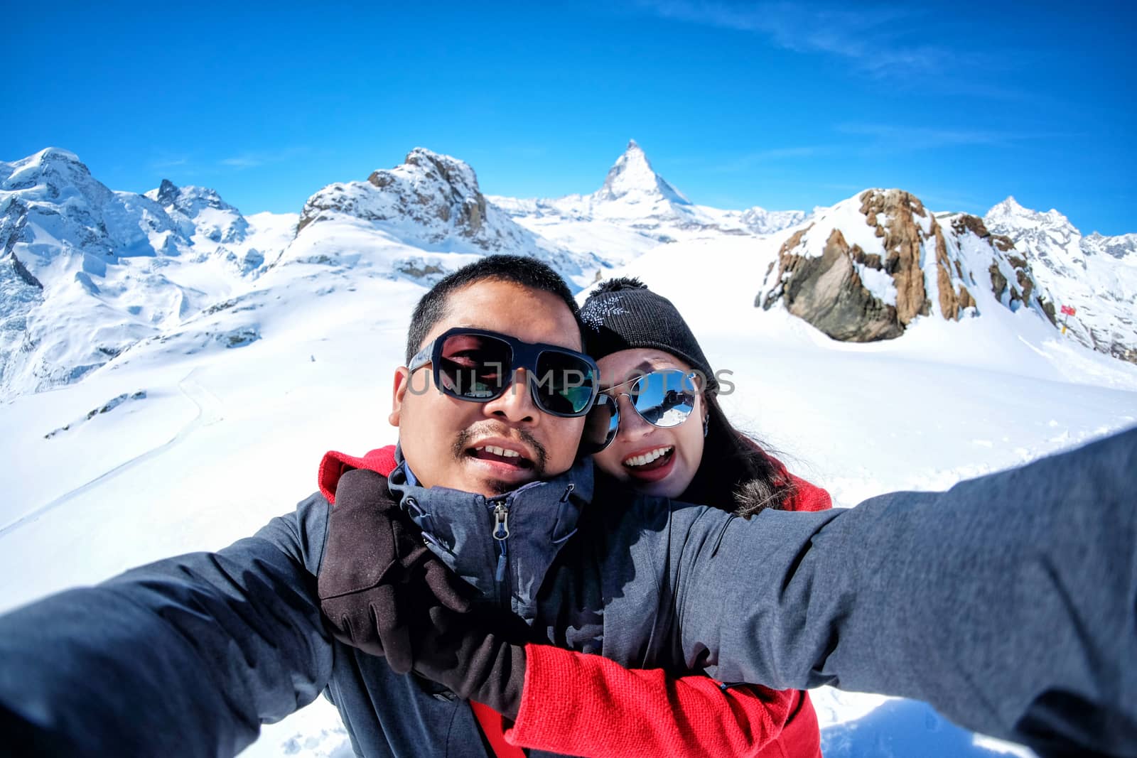 Young Couple Tourists selfie with mobile phone near view of snow mountain Matterhorn, Zermatt, Switzerland