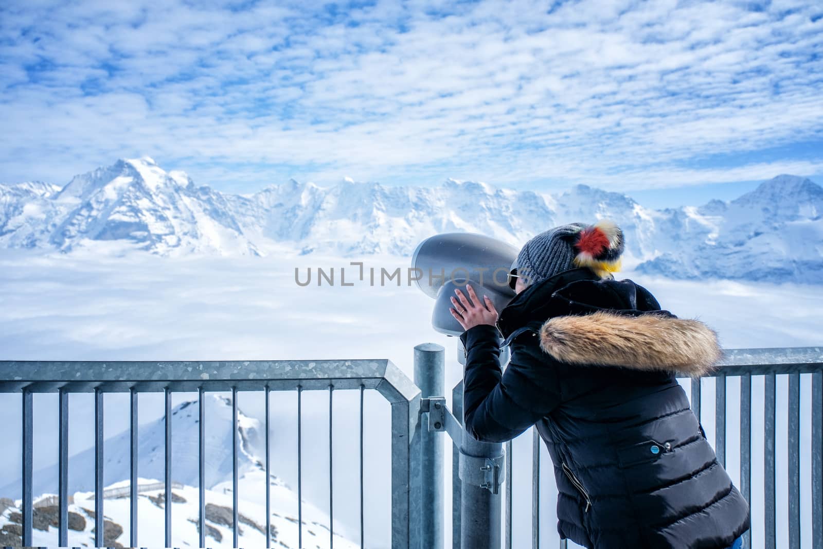 Young Woman Tourist at the Schilthorn using coin operated binocu by Surasak