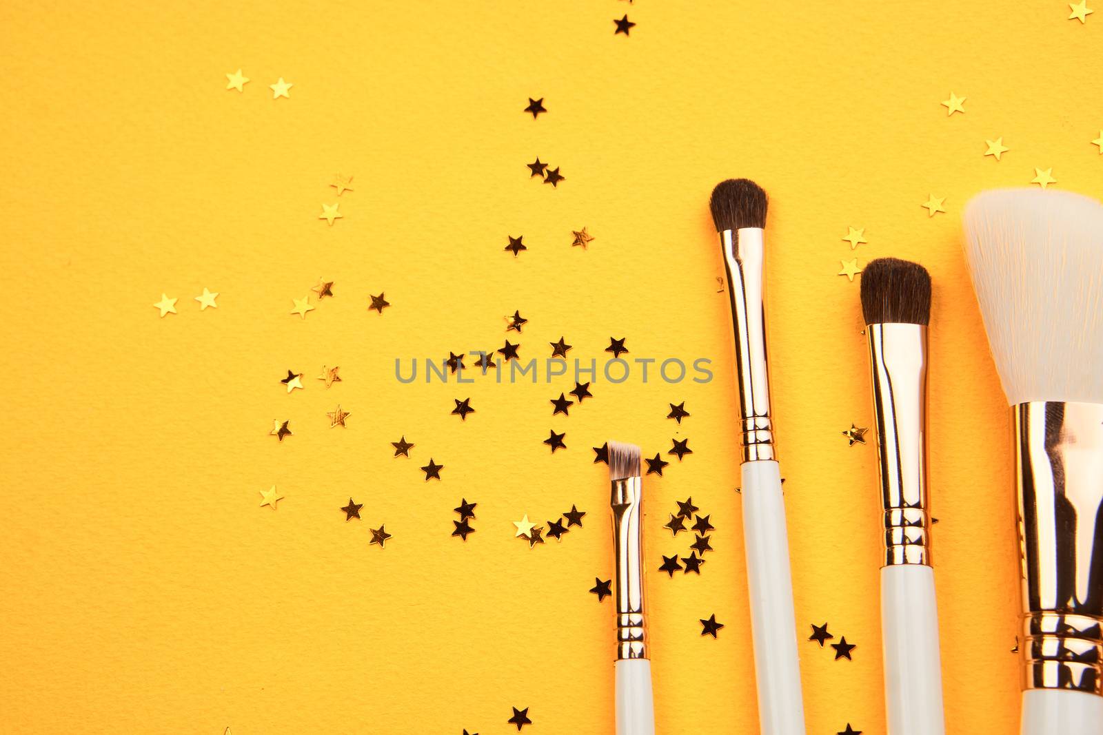 Makeup brushes in different sizes on a yellow background and glitter cropped look. High quality photo