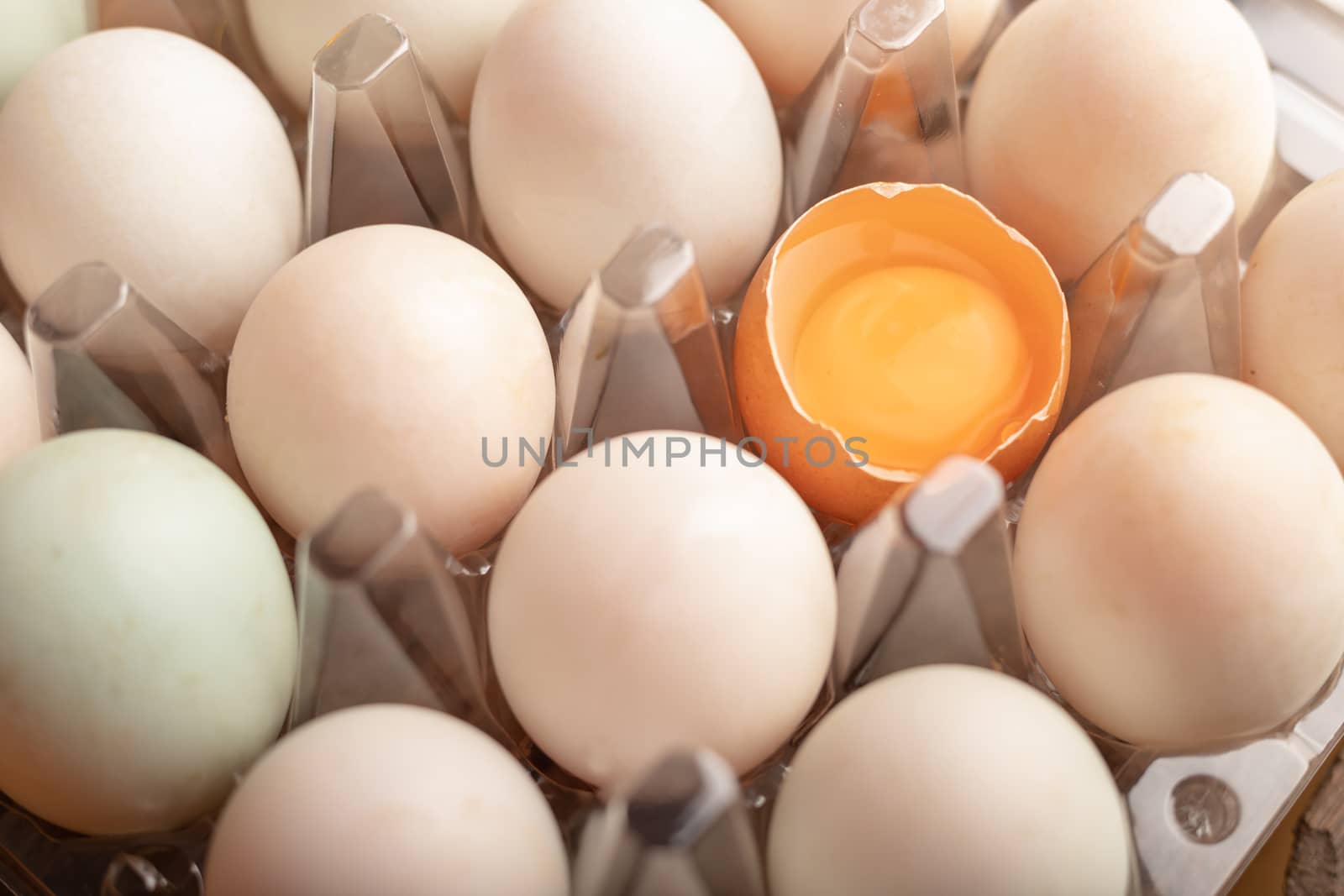 Close up broken eggs of chicken in plastic box on the wooden table. Yolk in peel. Select focus shallow depth of field.