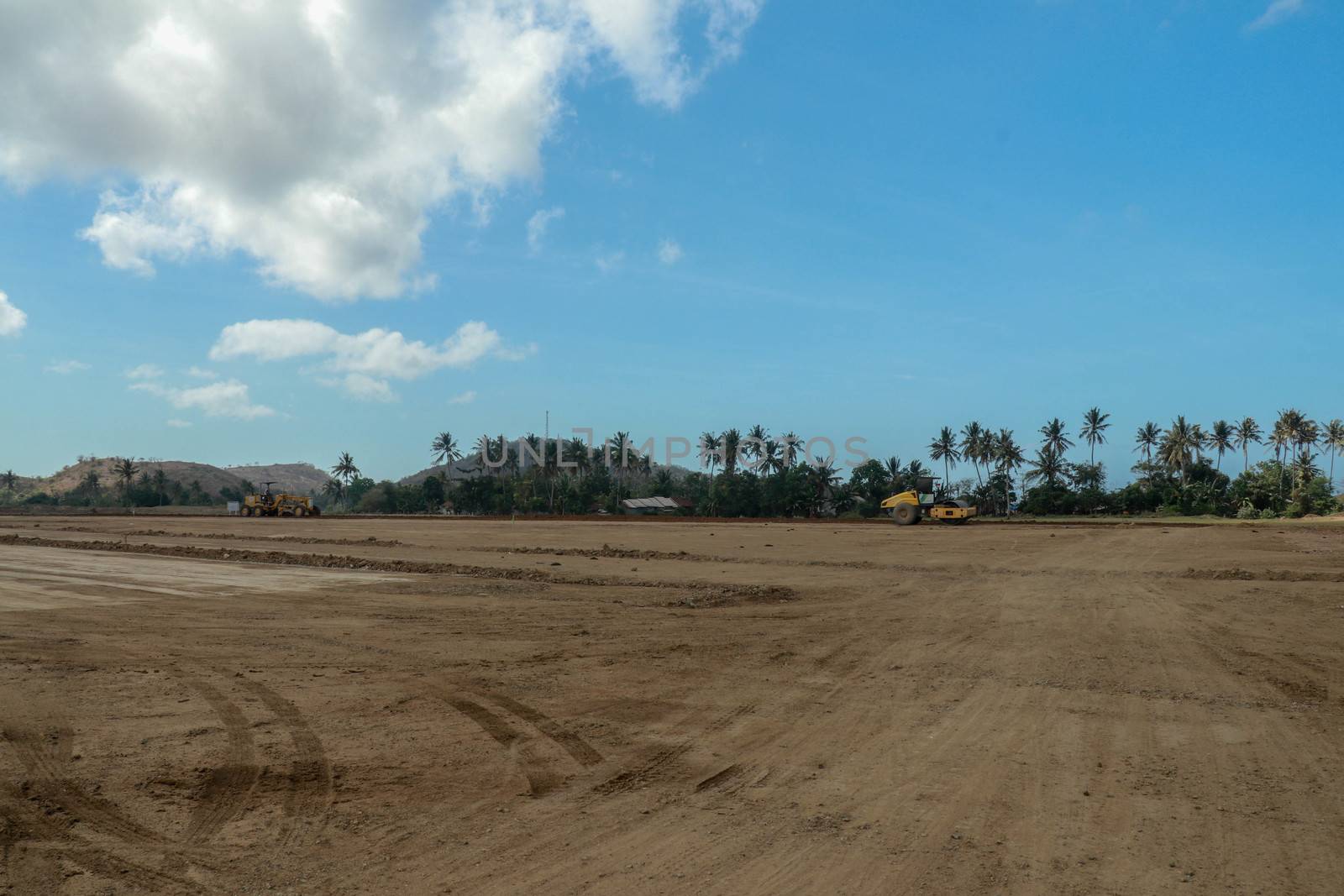 Working machines and heavy equipment adjust the terrain of the race track. Construction of the area and the Moto GP Mandalika racing circuit, West Nusa Tenggara, Lombok, Indonesia. Building a racetrack for motorcycles.