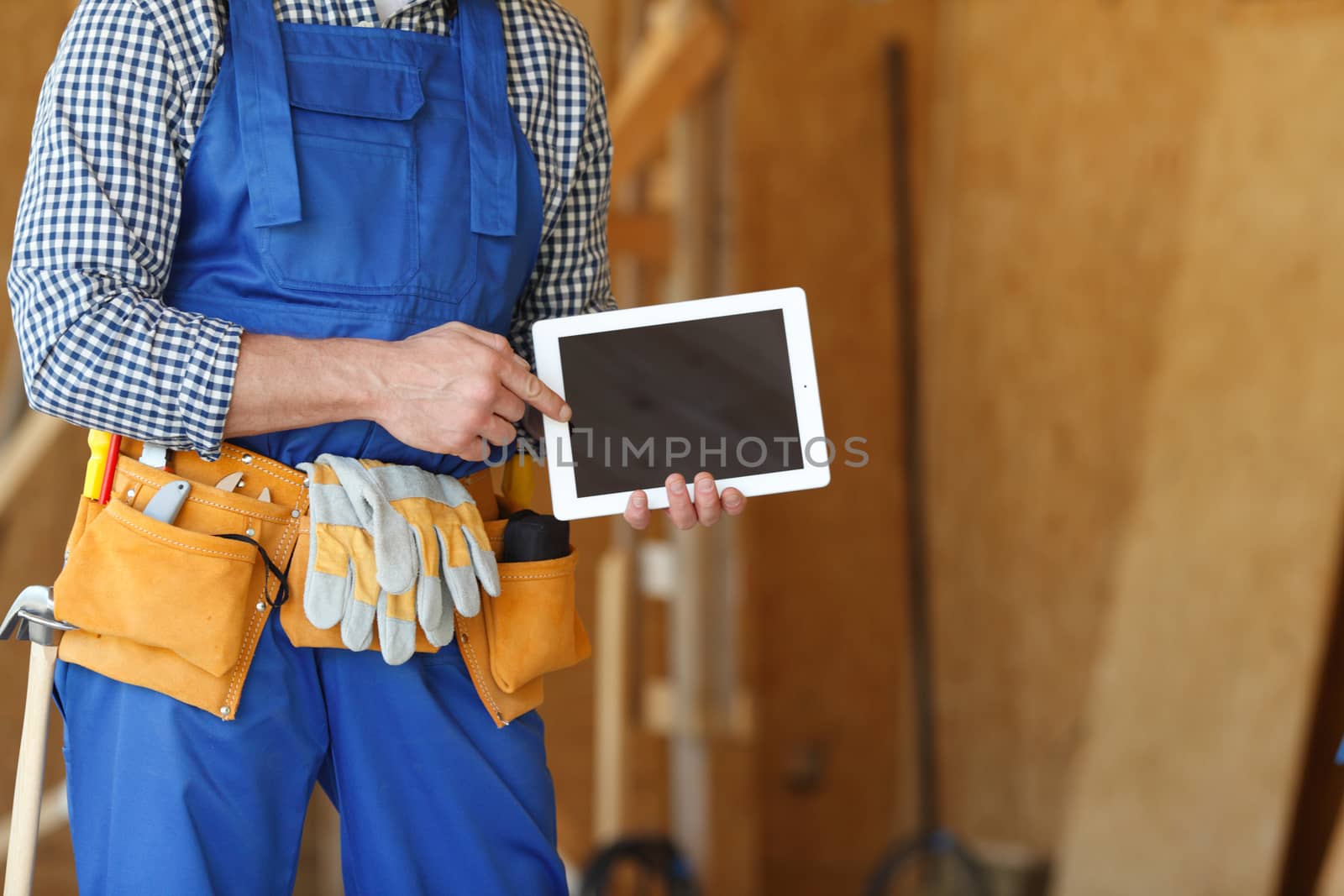 Construction worker at site pointing at blank digital tablet pc with copy space for text