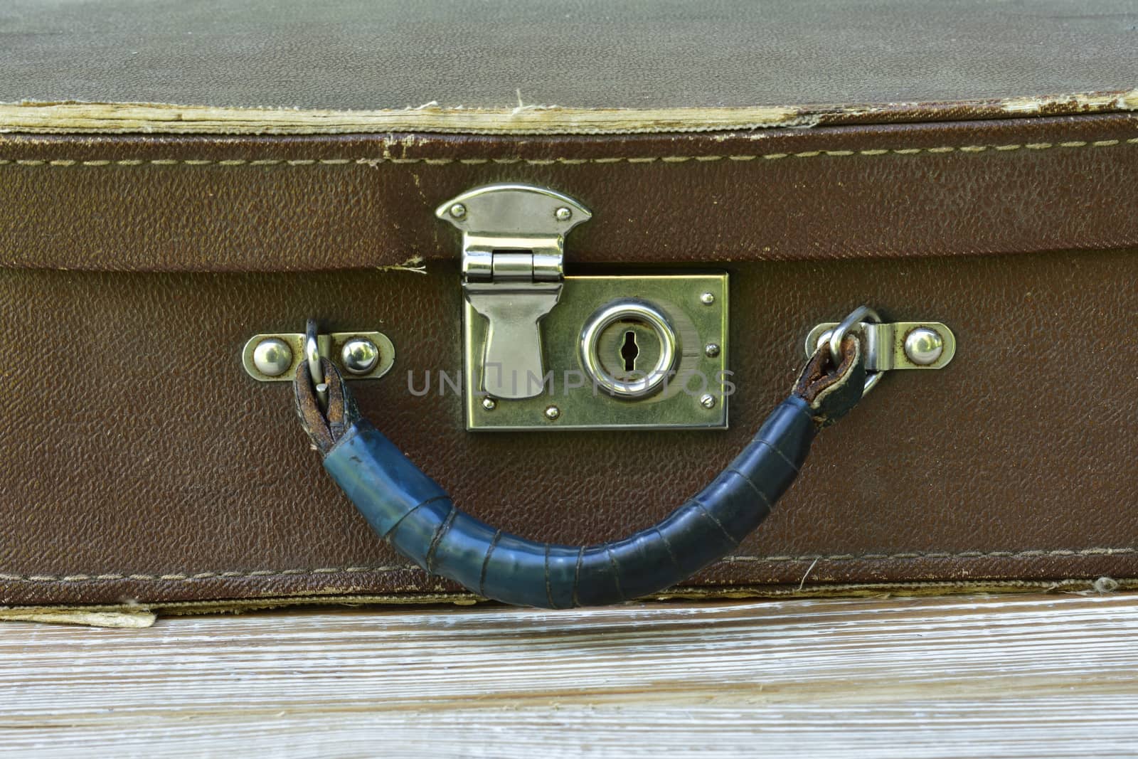  old suitcase lies on a shabby wooden table, front view close-up