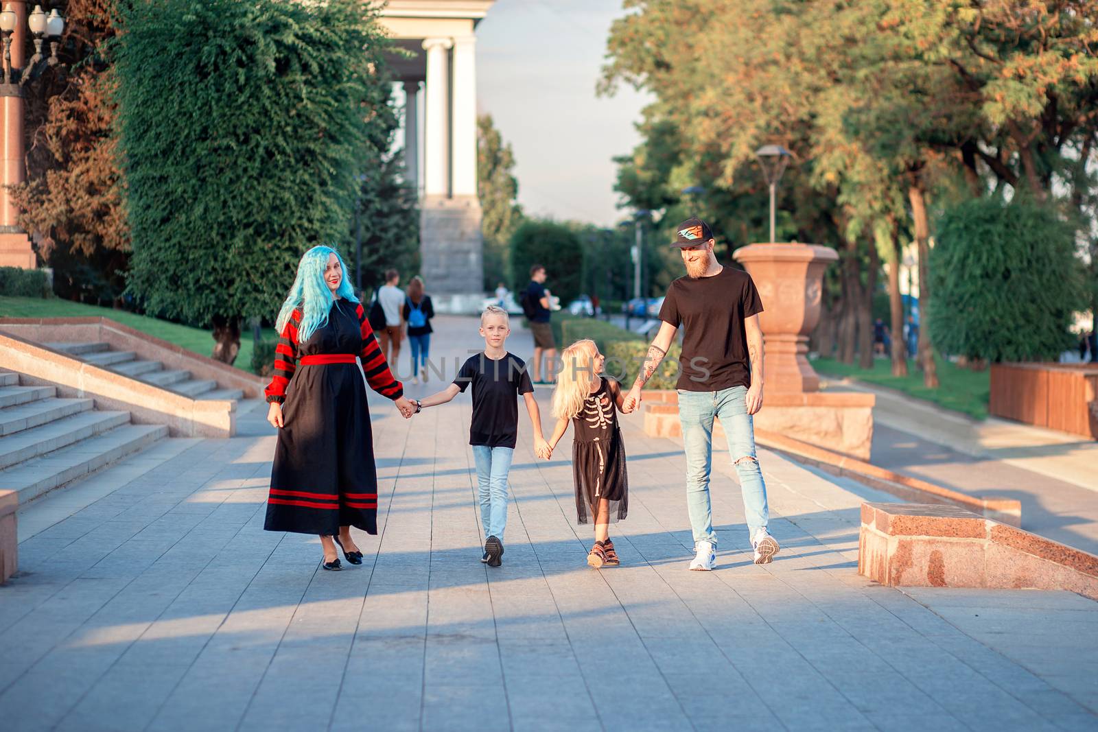 Unusual Family of four people are walking hand in hand in the park. Modern trend, unusual black punk style