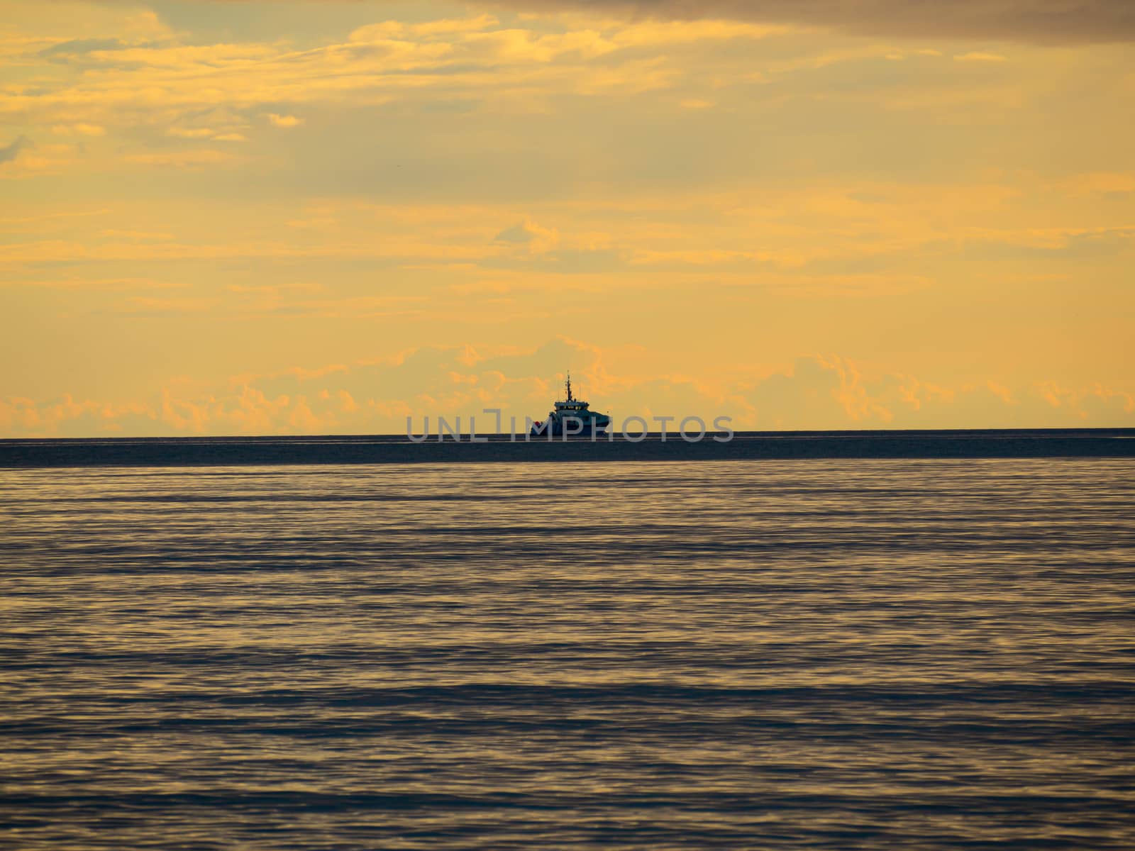 One small fishing boat heading out on the foggy ocean at dawn. Boat on the background of sunset. The Baltic Sea close up, stormy dramatic dark clouds. The Vacation, summer concept