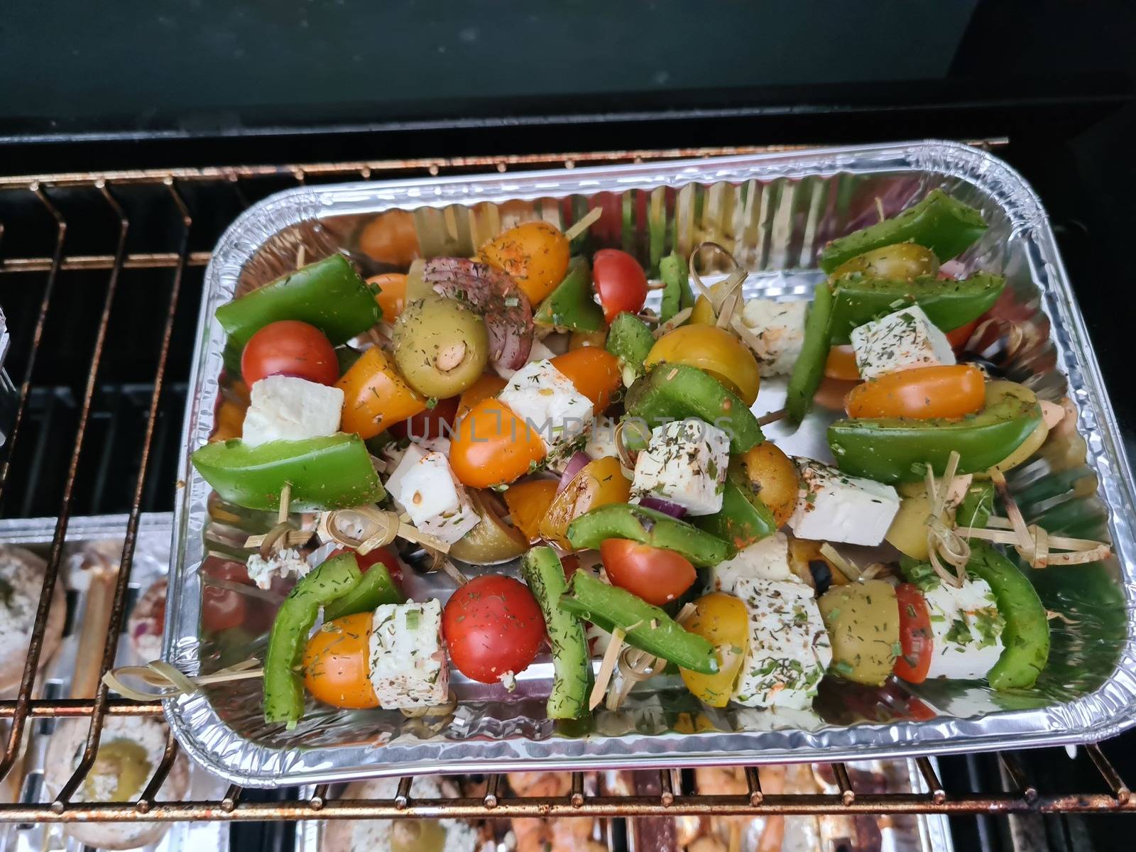 Grilled skewers with mixed vegetables served on a wooden cutting board with a vegan herb dip