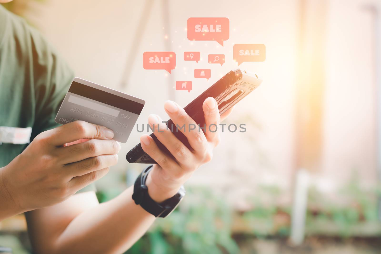 Shopping online concept. Hand holding black smartphone with red popup sale icon and credit card. Black Friday and shop at home.