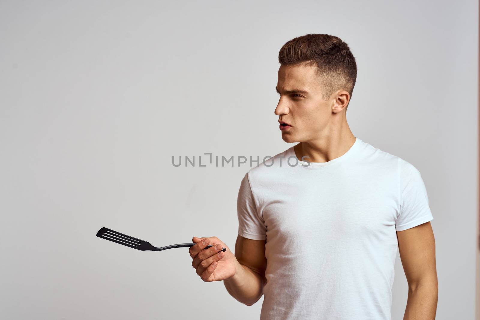 A man with a shovel in his hand interested look light background. High quality photo