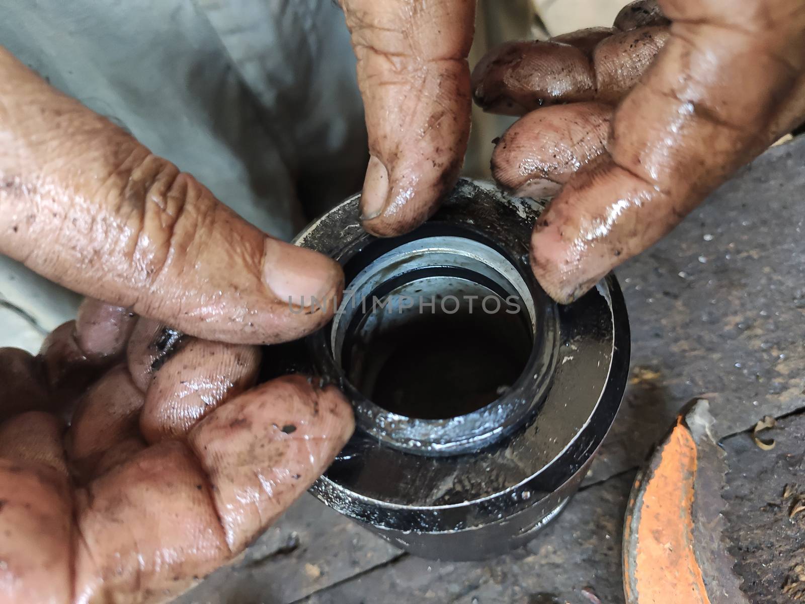 Dirty mechanic's hands work on a small metalwork piece