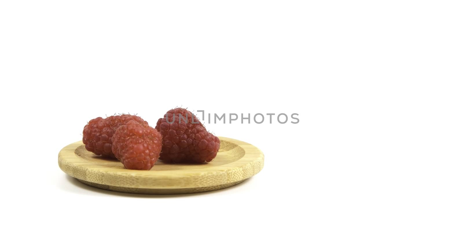 Ripe tasty bright Fresh raspberry in a wicker basket on a cutting board on a white background. High quality photo