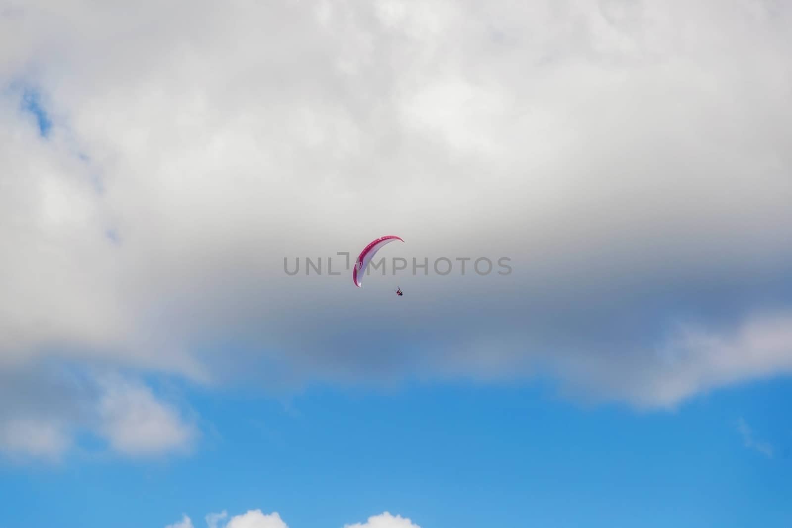 One paraglider is flying in the blue sky against the background of clouds. Paragliding in the sky on a sunny day.