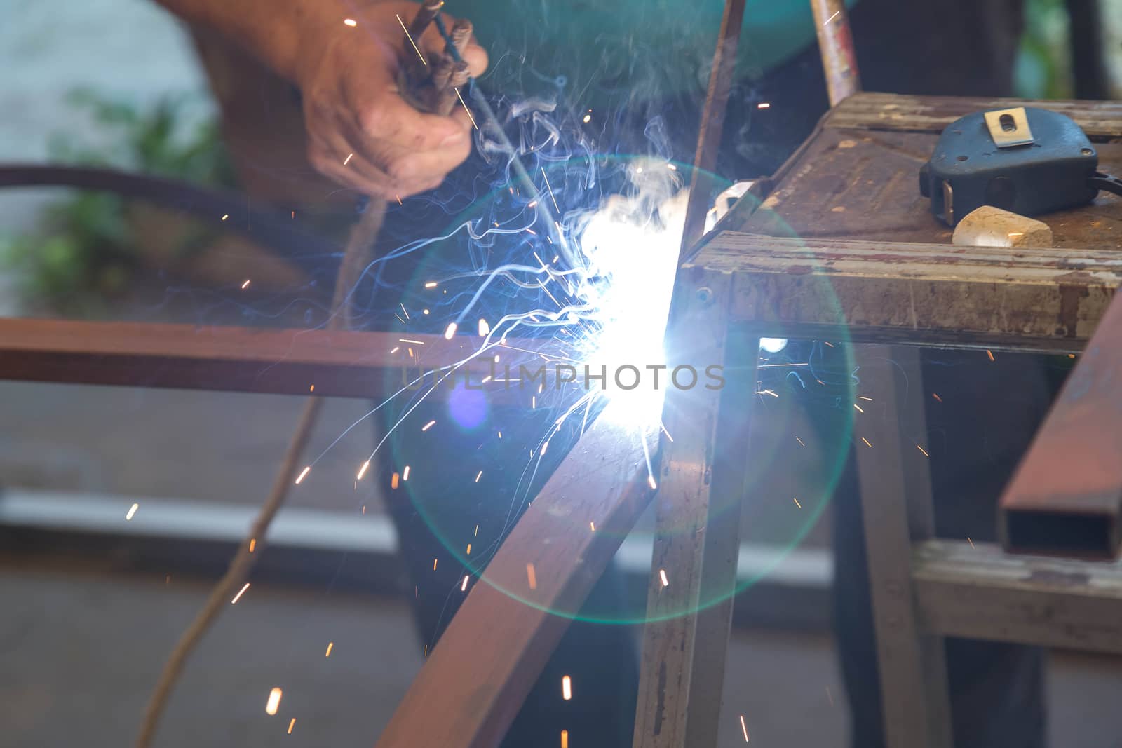 Close-up of hands A man holding a welding machine and doing spot welding  by galinasharapova