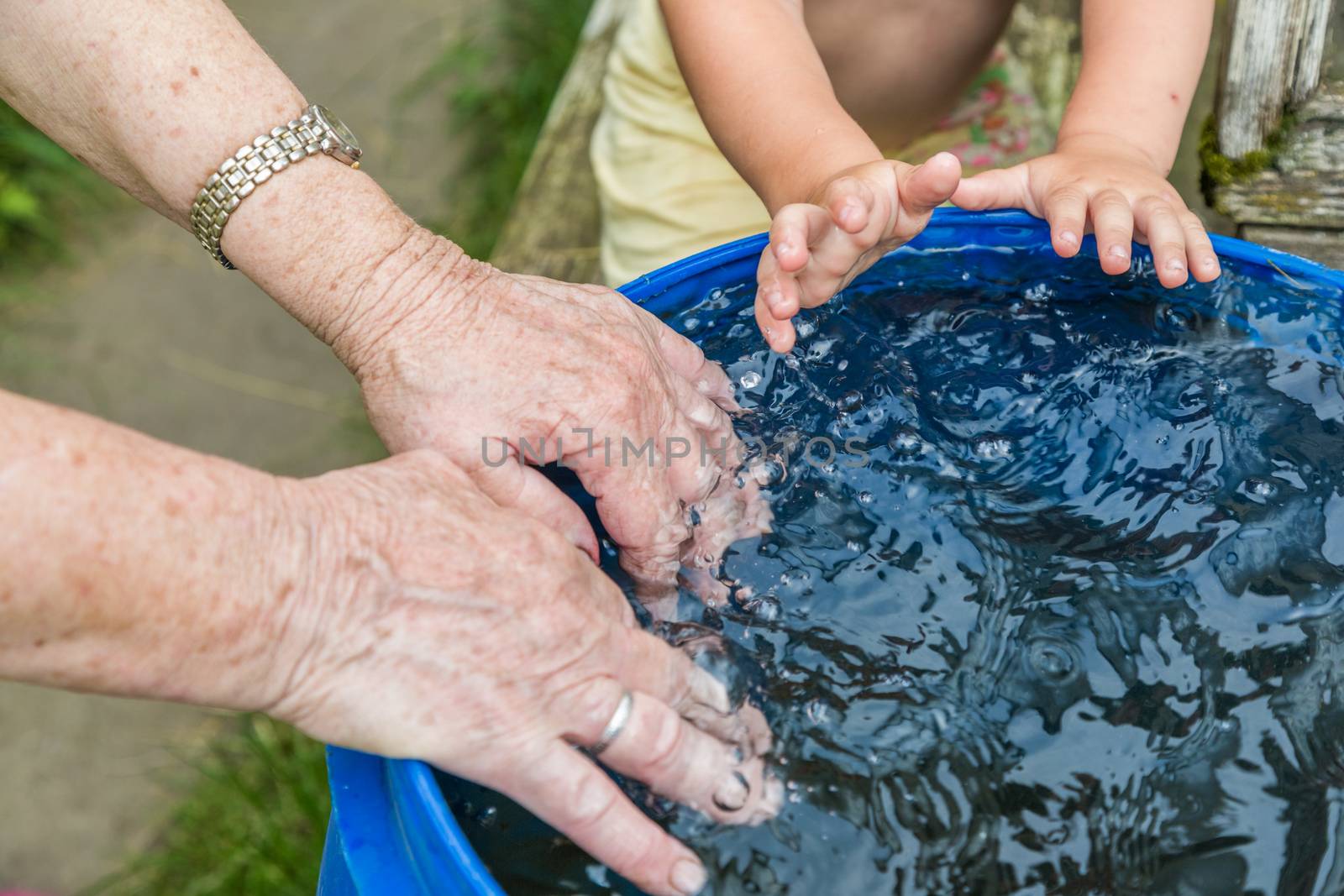A boy and hos grandmother wash hands in the water barrel.