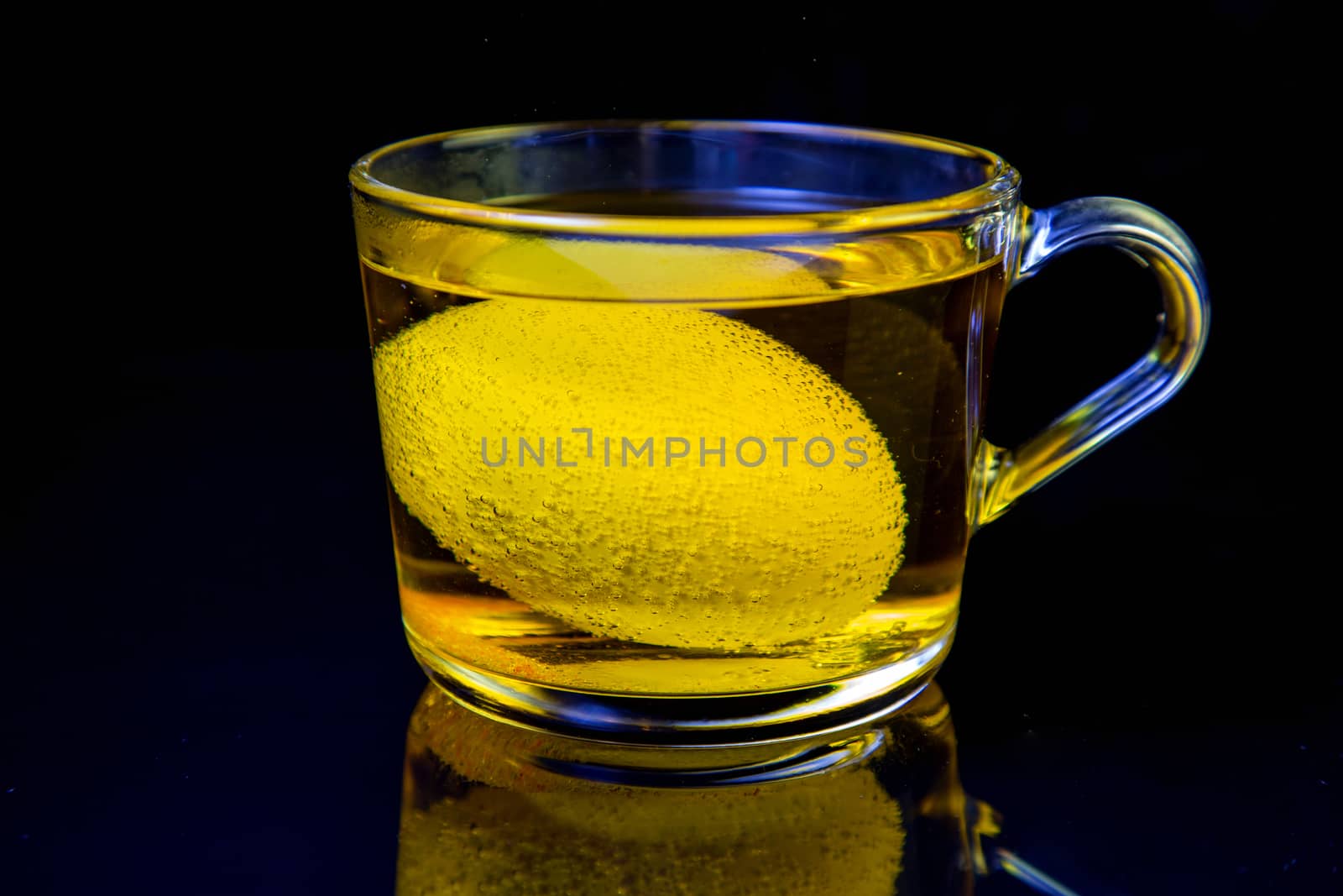 the process of dyeing eggs for Easter. egg in a transparent mug with dye. close-up on black background